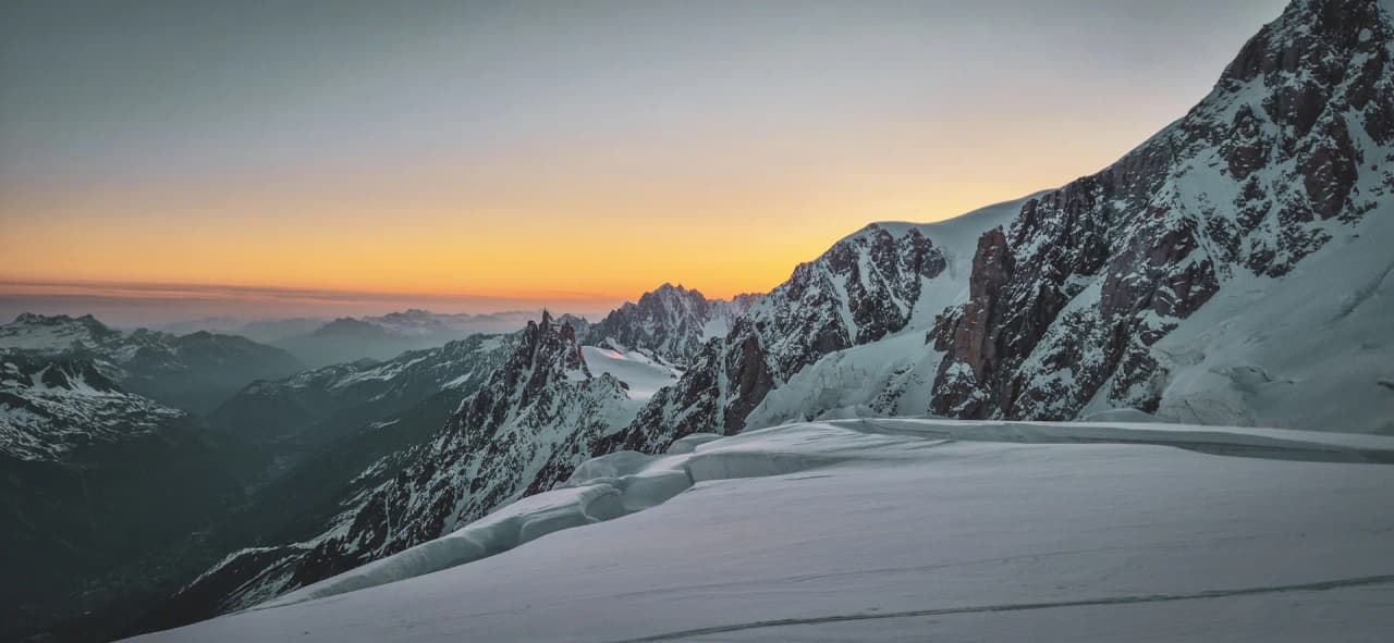 Paysage alpin spectaculaire au coucher du soleil, neige éblouissante et sommets majestueux.
