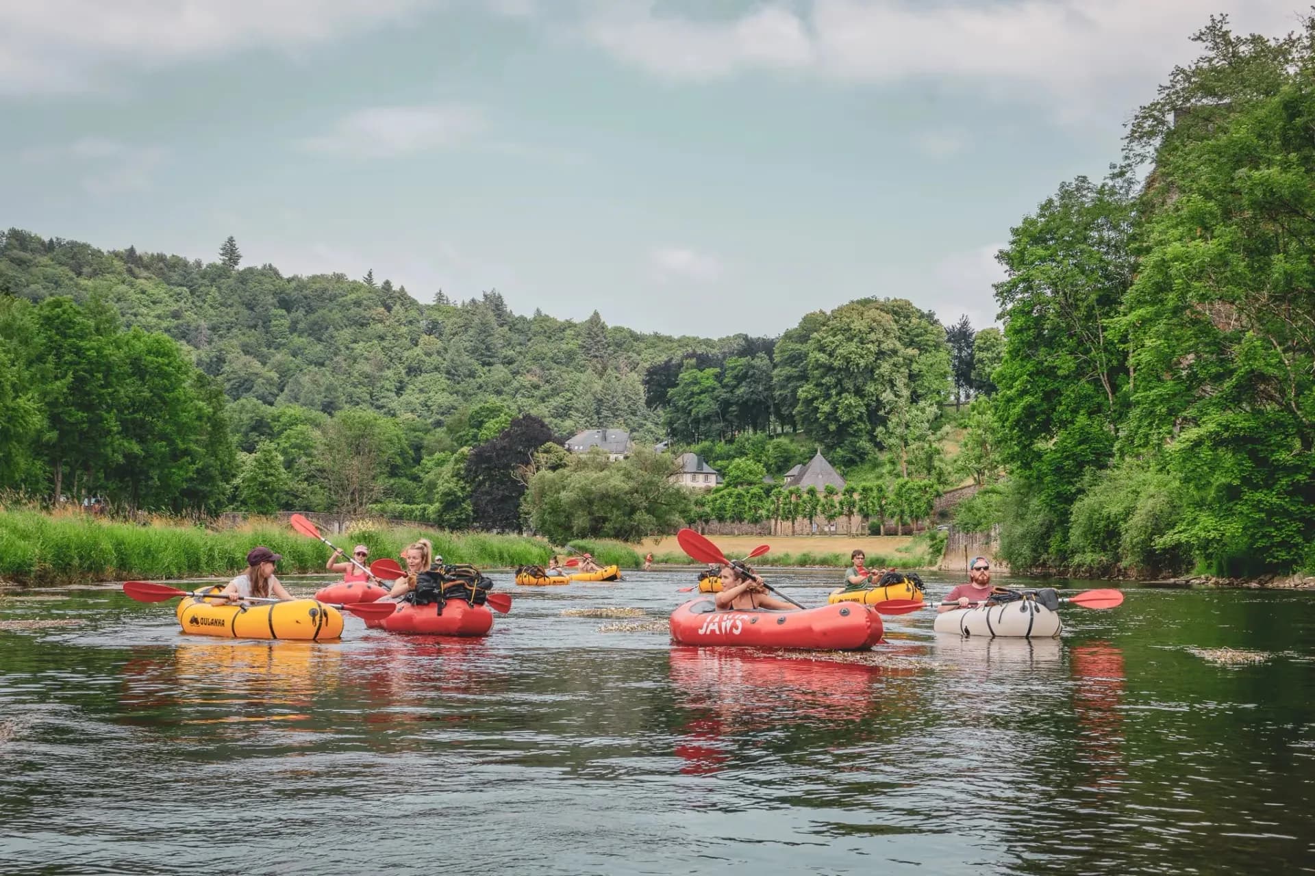 Een groep backpackers vaart vredig over de Semois, omringd door een weelderig groen landschap.