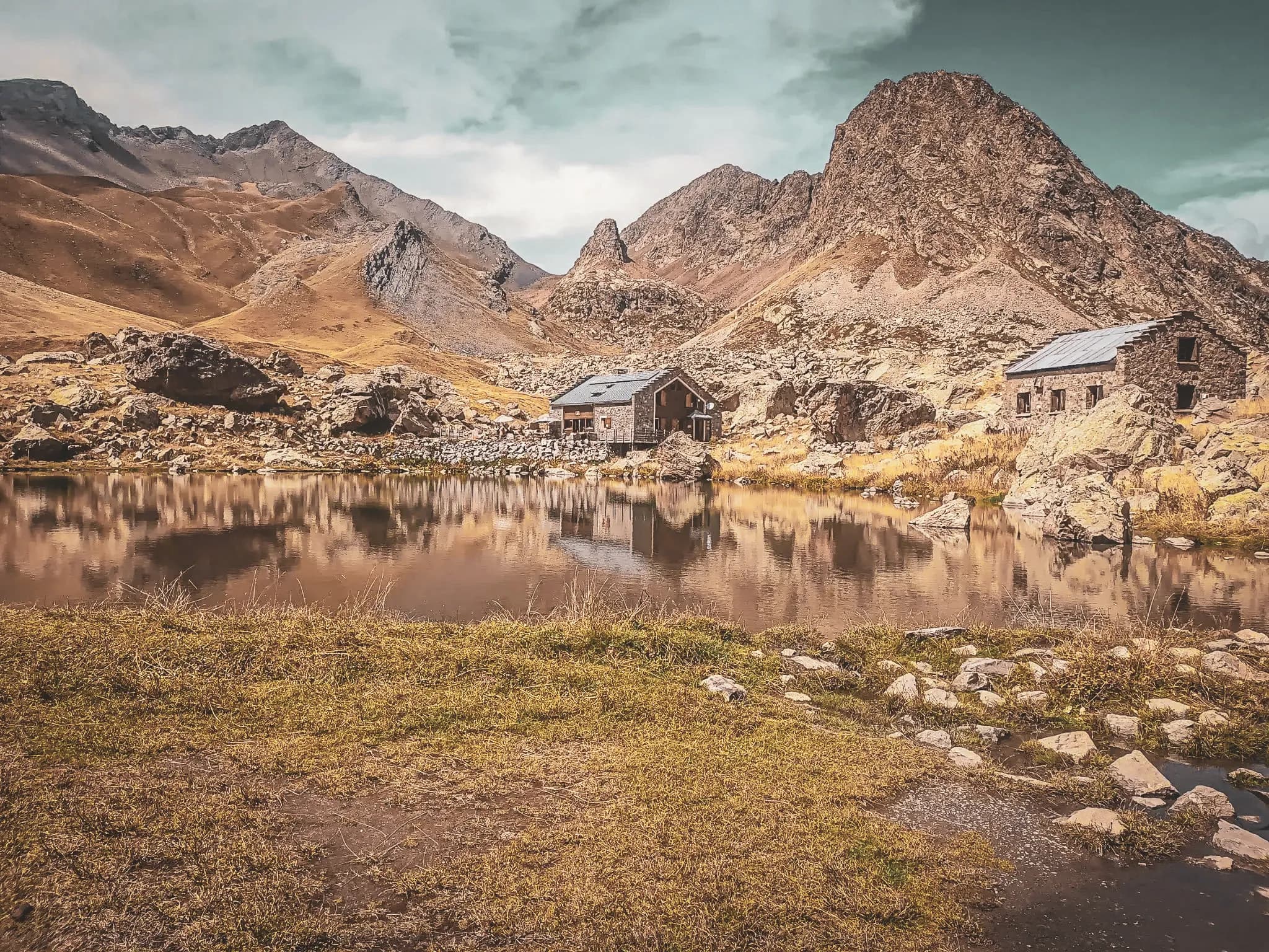 Refuge pittoresque au bord d'un lac, entouré de montagnes majestueuses et de paysages sauvages.