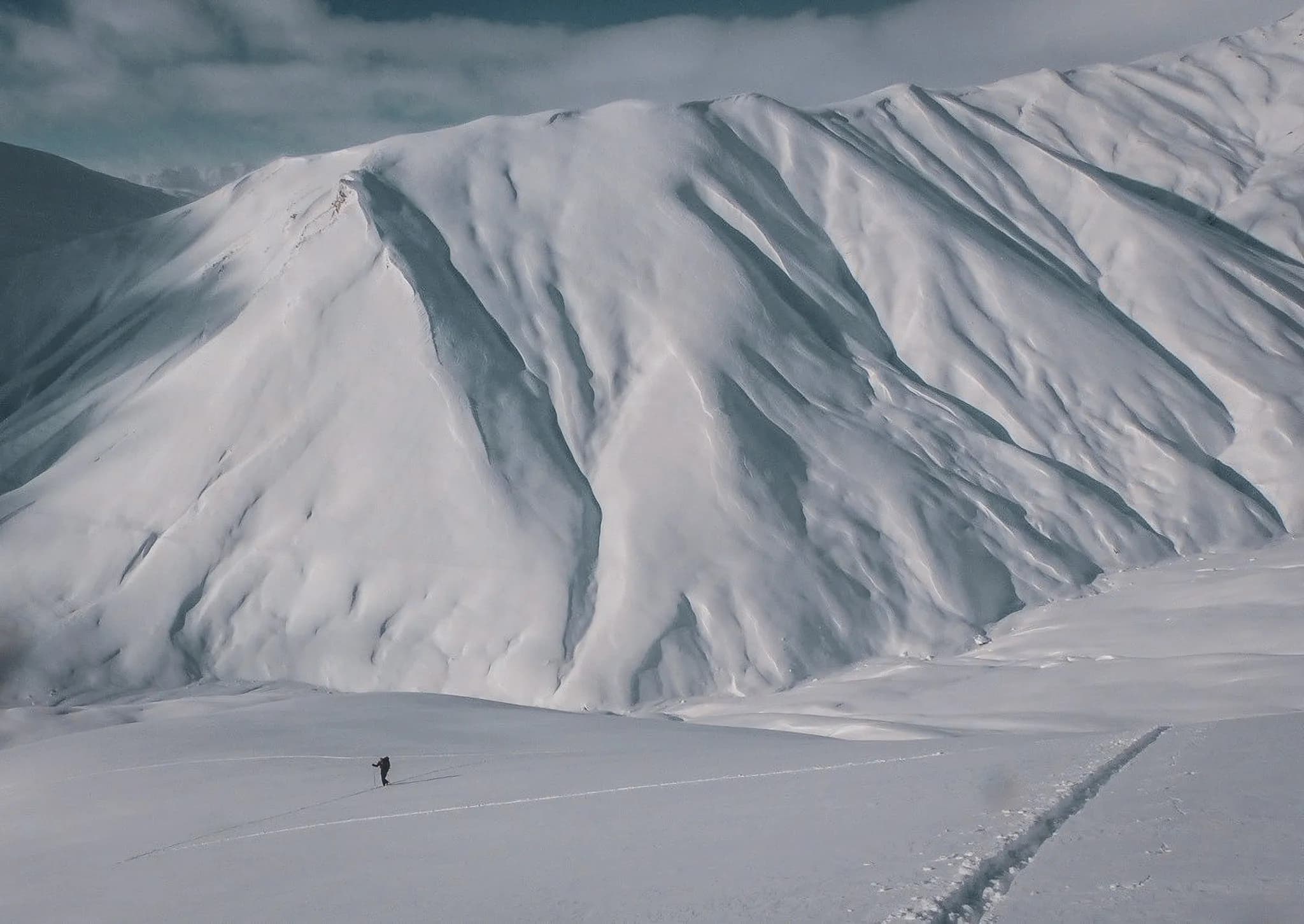 Een skiër baant zich een weg door een majestueus landschap van besneeuwde bergen, een uitnodiging tot avontuur.