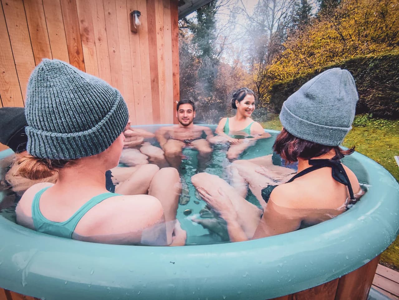 Een groep mensen ontspant in een Scandinavisch bad, omringd door de zinderende natuur.