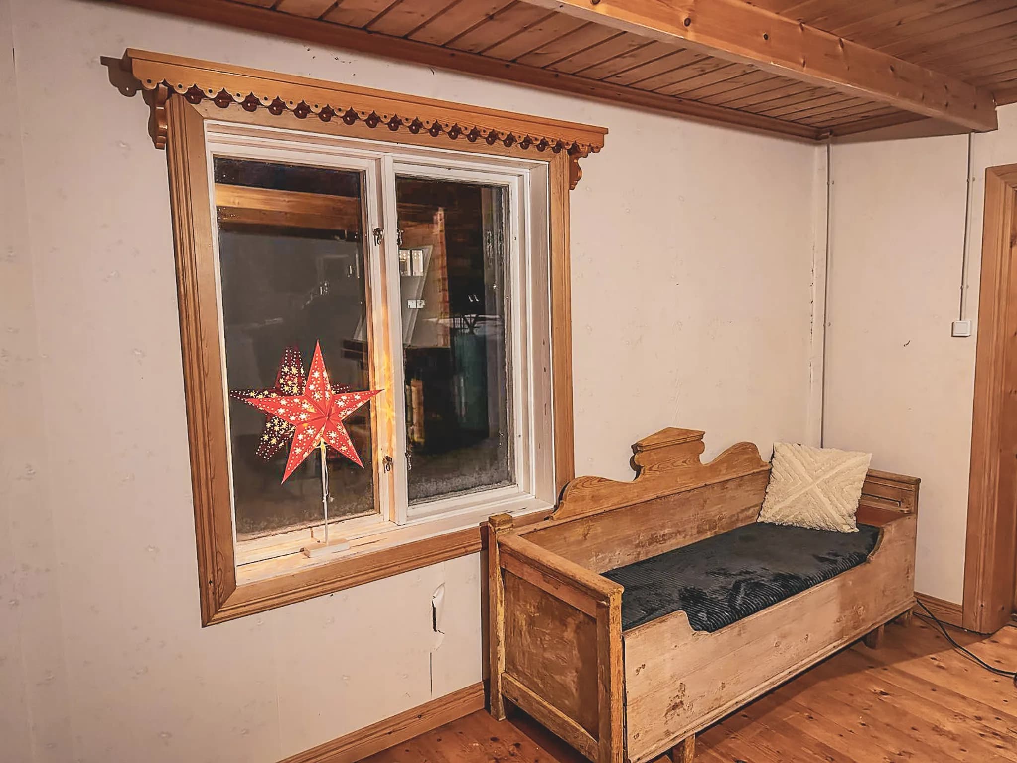 Het gezellige interieur van een hut in Lapland, met een houten bank en een ster voor het raam.