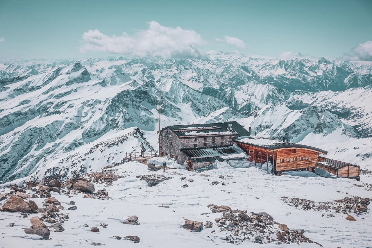 An alpine mountain hut surrounded by glaciers and snow-capped peaks. Escape and adventure!
