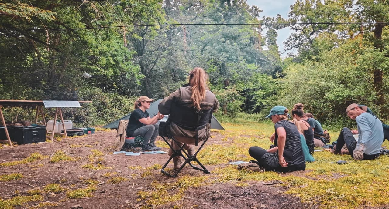 Groupe en pleine session de survie en forêt, apprenant des techniques essentielles en nature.