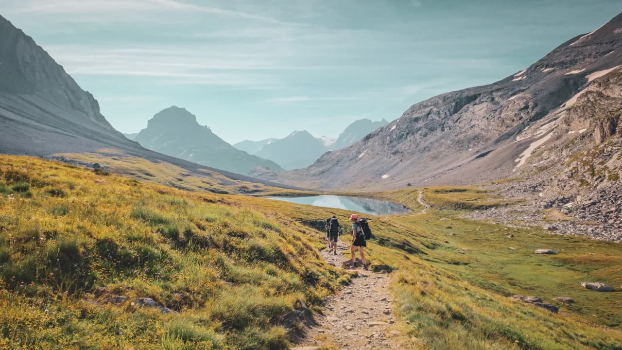 Hikers on their way to a high-altitude lake, surrounded by majestic peaks and flower-filled meadows.