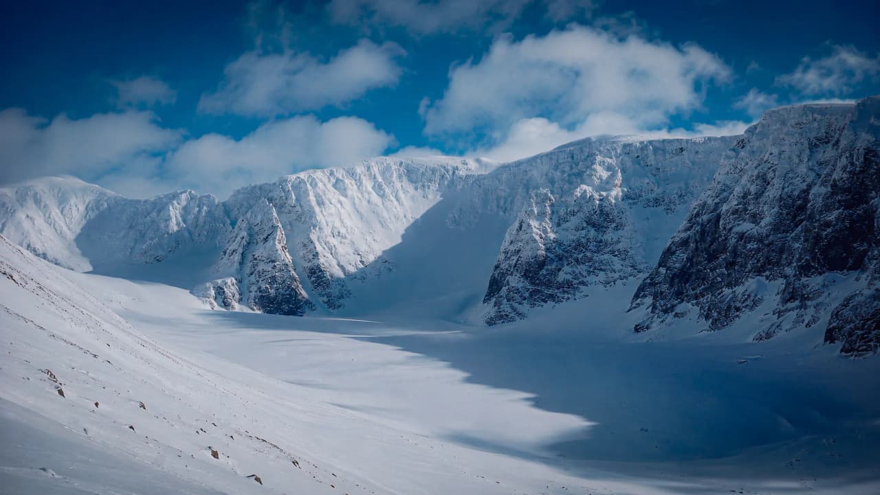 Een majestueus landschap van besneeuwde bergen onder een blauwe hemel, dat uitnodigt tot avontuur in Lapland.