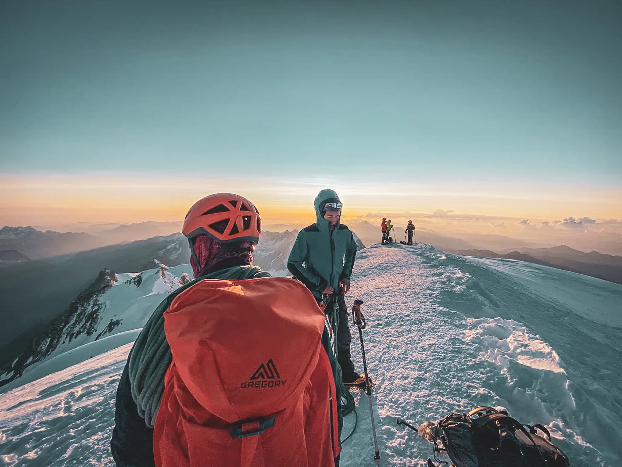 Des aventuriers admirent le lever du soleil depuis le sommet enneigé du Mont Blanc.