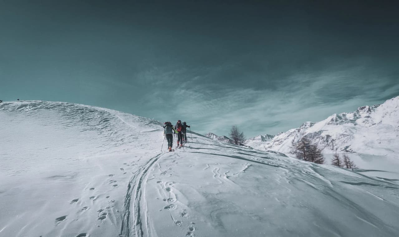 Des randonneurs explorent les pentes enneigées du Mont Viso, sous un ciel dégagé et majestueux.