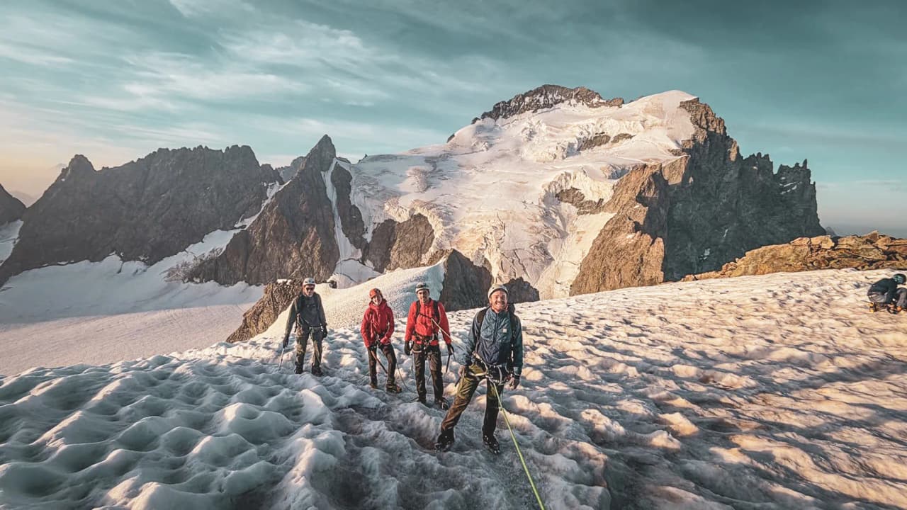 Groupe d'alpinistes sur un glacier, émerveillés par les sommets majestueux des Écrins.