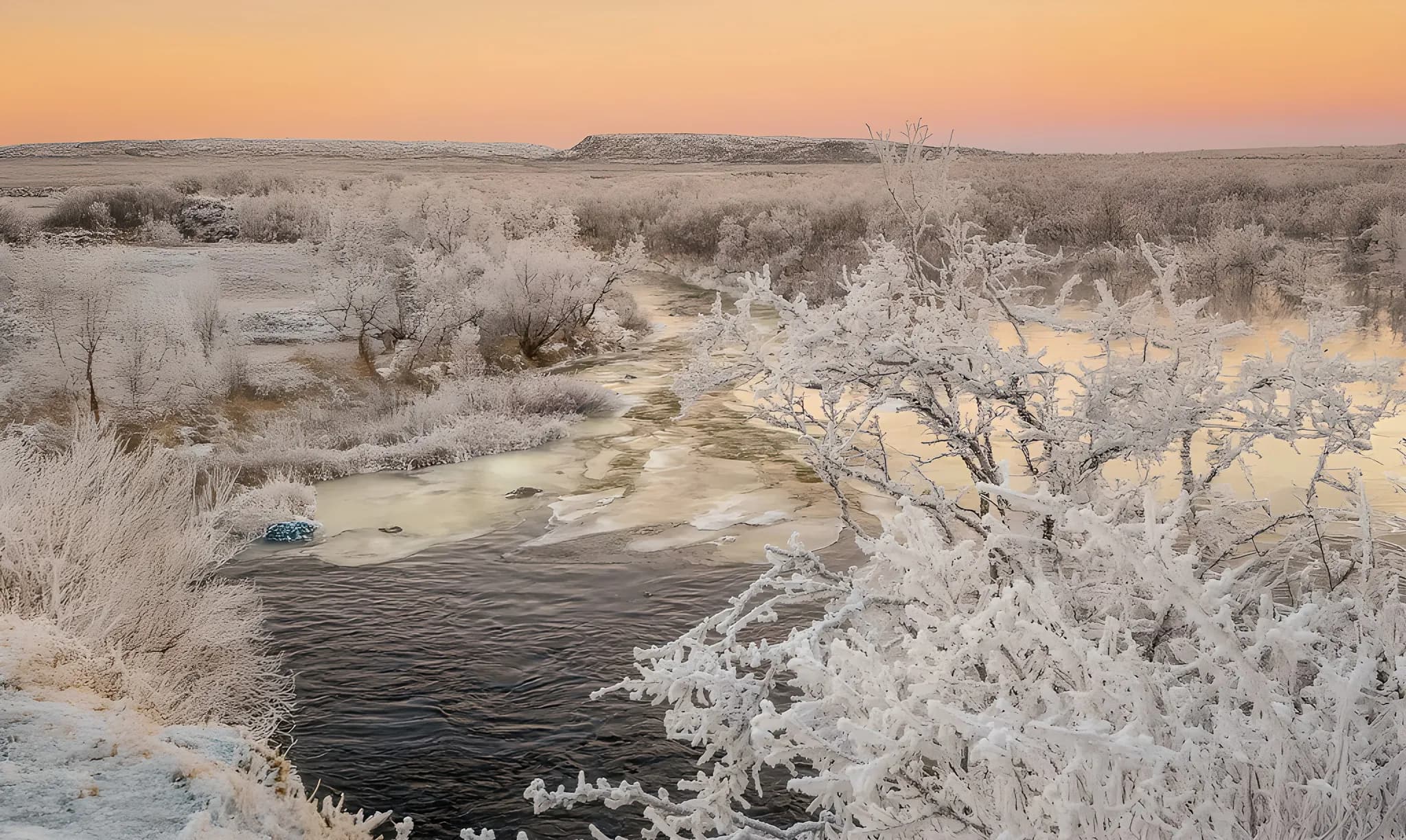 A magical winter landscape with frosted trees and a sparkling river under a colourful sky.