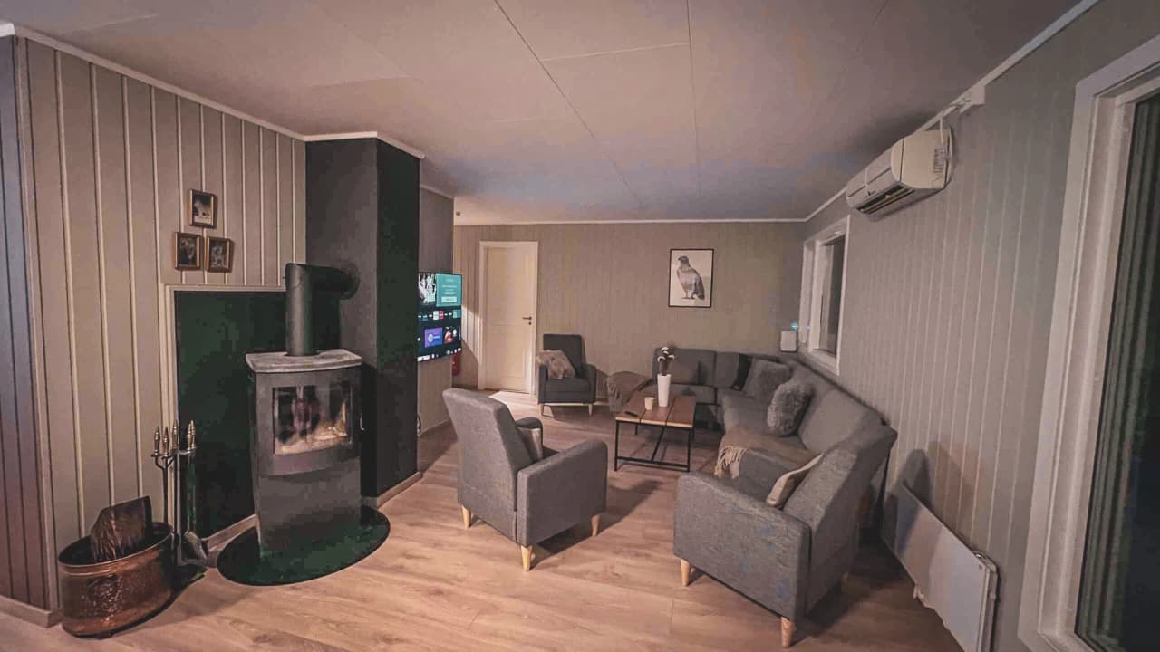 Gezellige woonkamer met kachel en moderne meubels, ideaal om even bij te komen na avonturen in de buitenlucht.