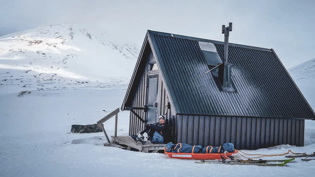 Een houten Berghut aan de rand van de sneeuw, ski's en pulka, een uitnodiging voor avontuur in Lapland.