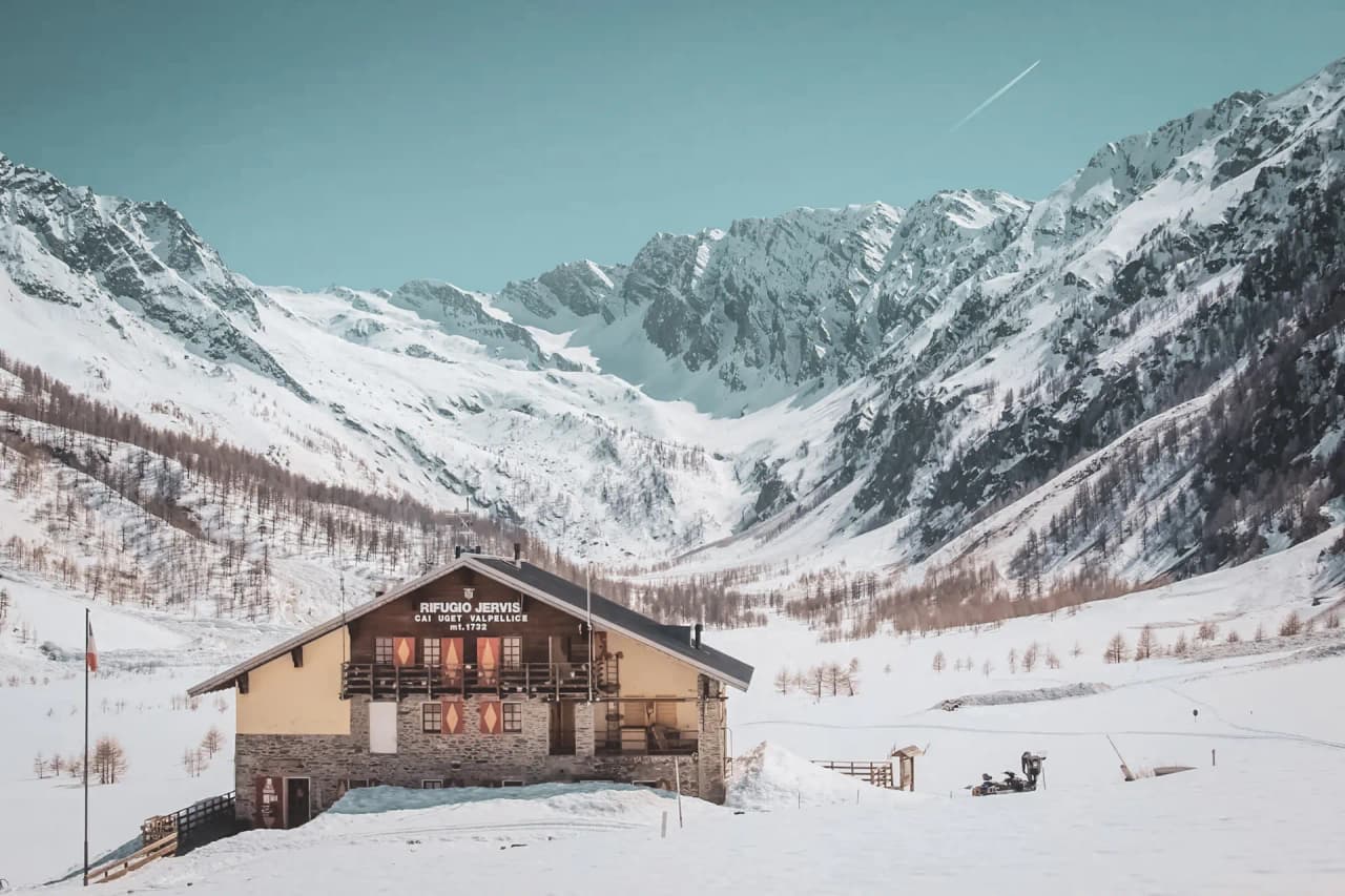 Refuge en pleine montagne, entouré de sommets enneigés et de paysages alpins à couper le souffle.