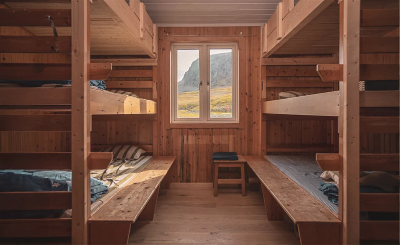 The cosy interior of a wooden inn, with bunk beds and views over the Lapland landscape.