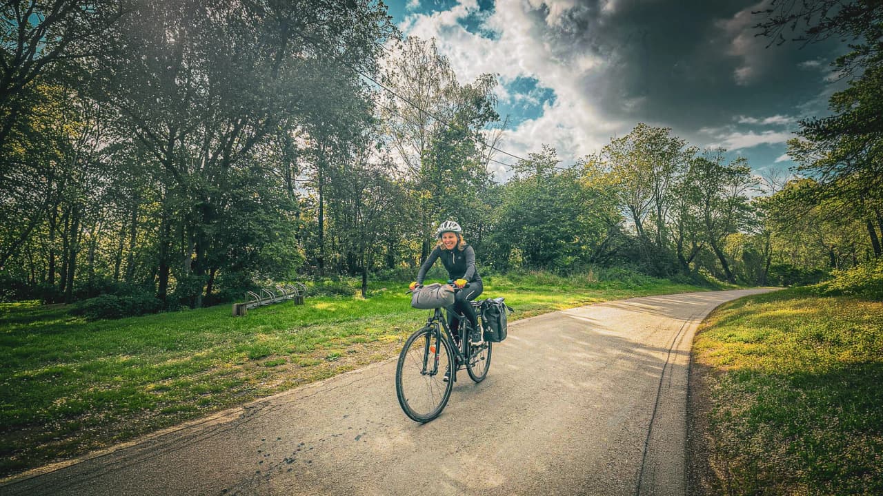 Een lachende fietser op een weg met weelderig groene bossen, perfect voor avontuur.