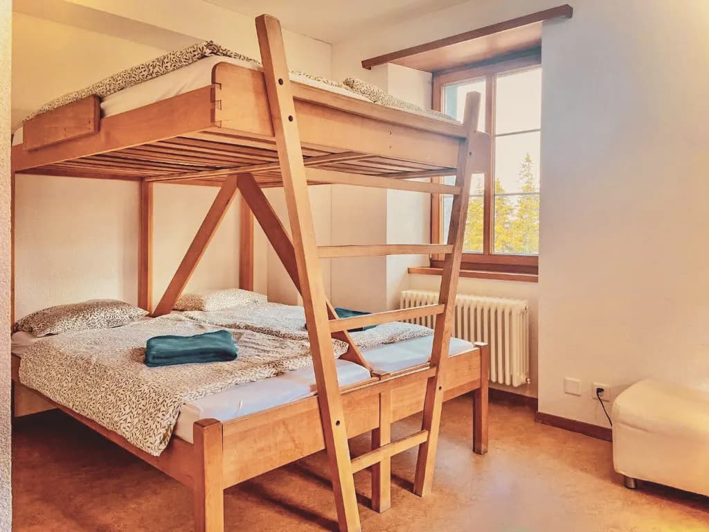 Chambre chaleureuse avec lits superposés, idéale pour une escapade en raquettes dans le Jura.