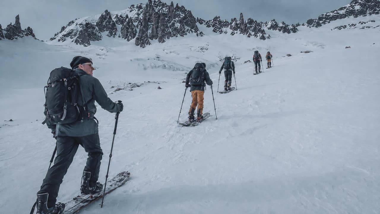 Groupe d'aventuriers en splitboard progressant dans un paysage alpin enneigé autour du Mont-Blanc.