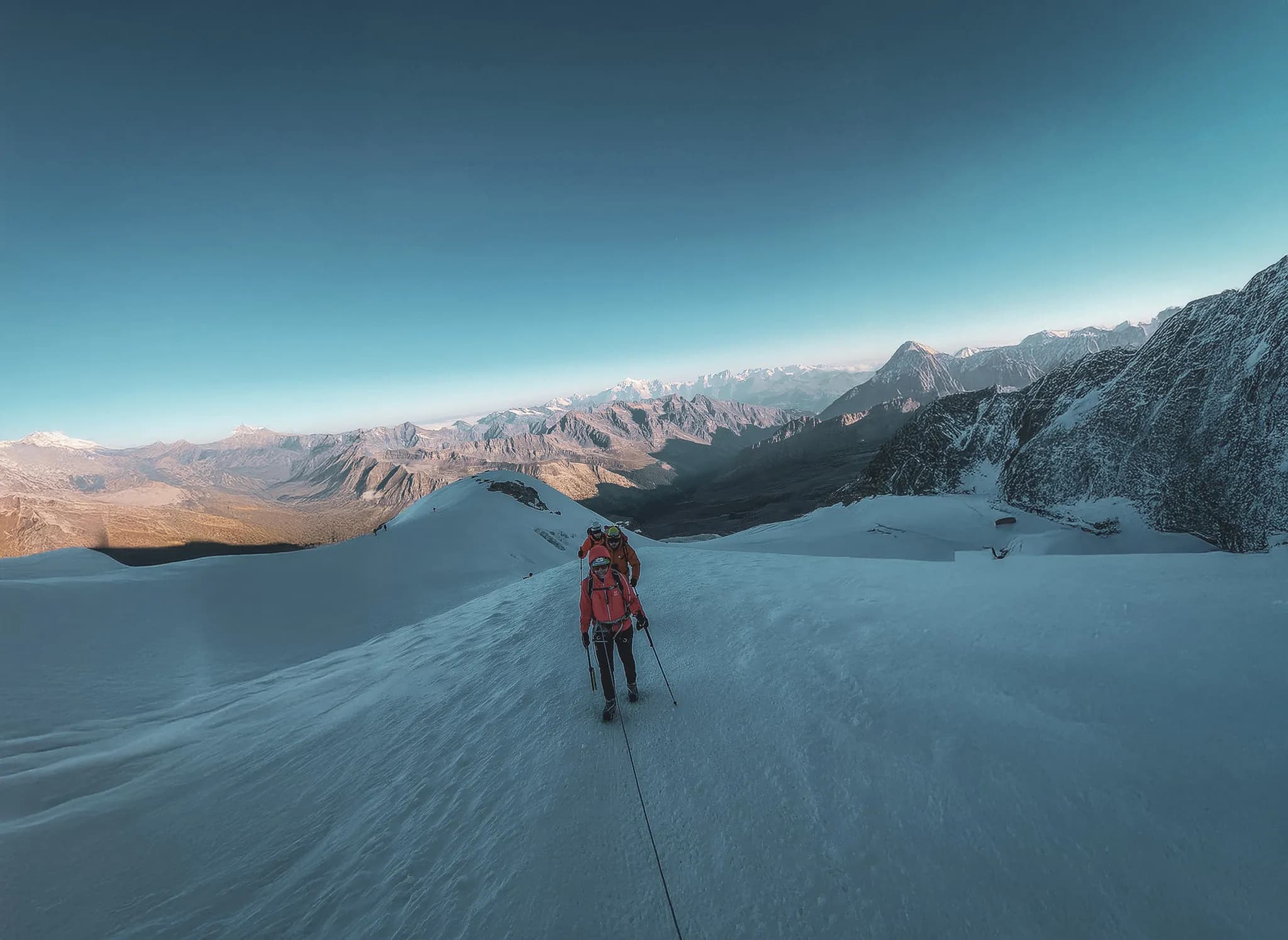 Mountaineers on a glacial ridge, with majestic peaks in the background. An exceptional adventure!