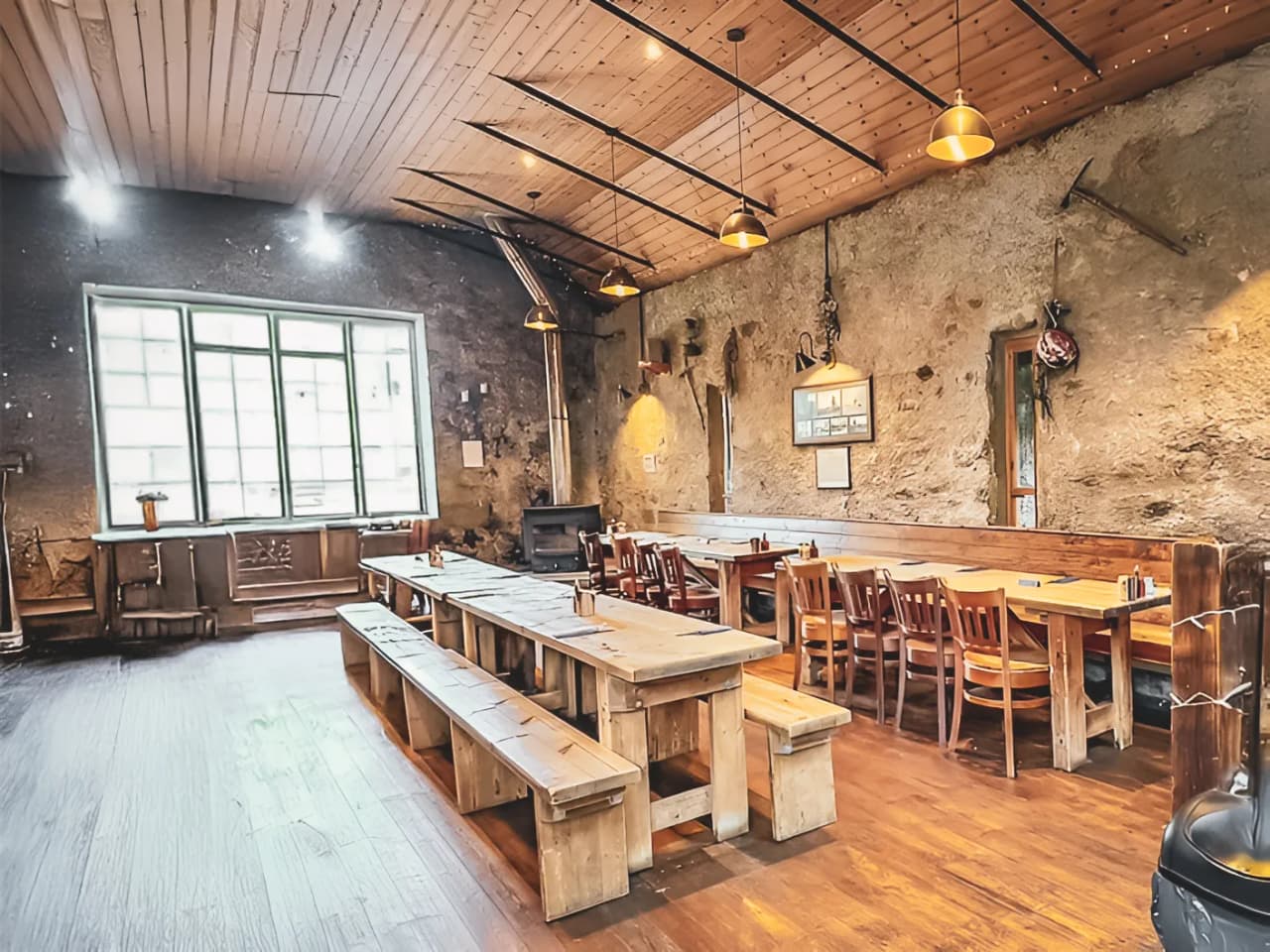 Een rustieke en gezellige ruimte met houten tafels, badend in het licht, perfect voor een maaltijd na een avontuur.