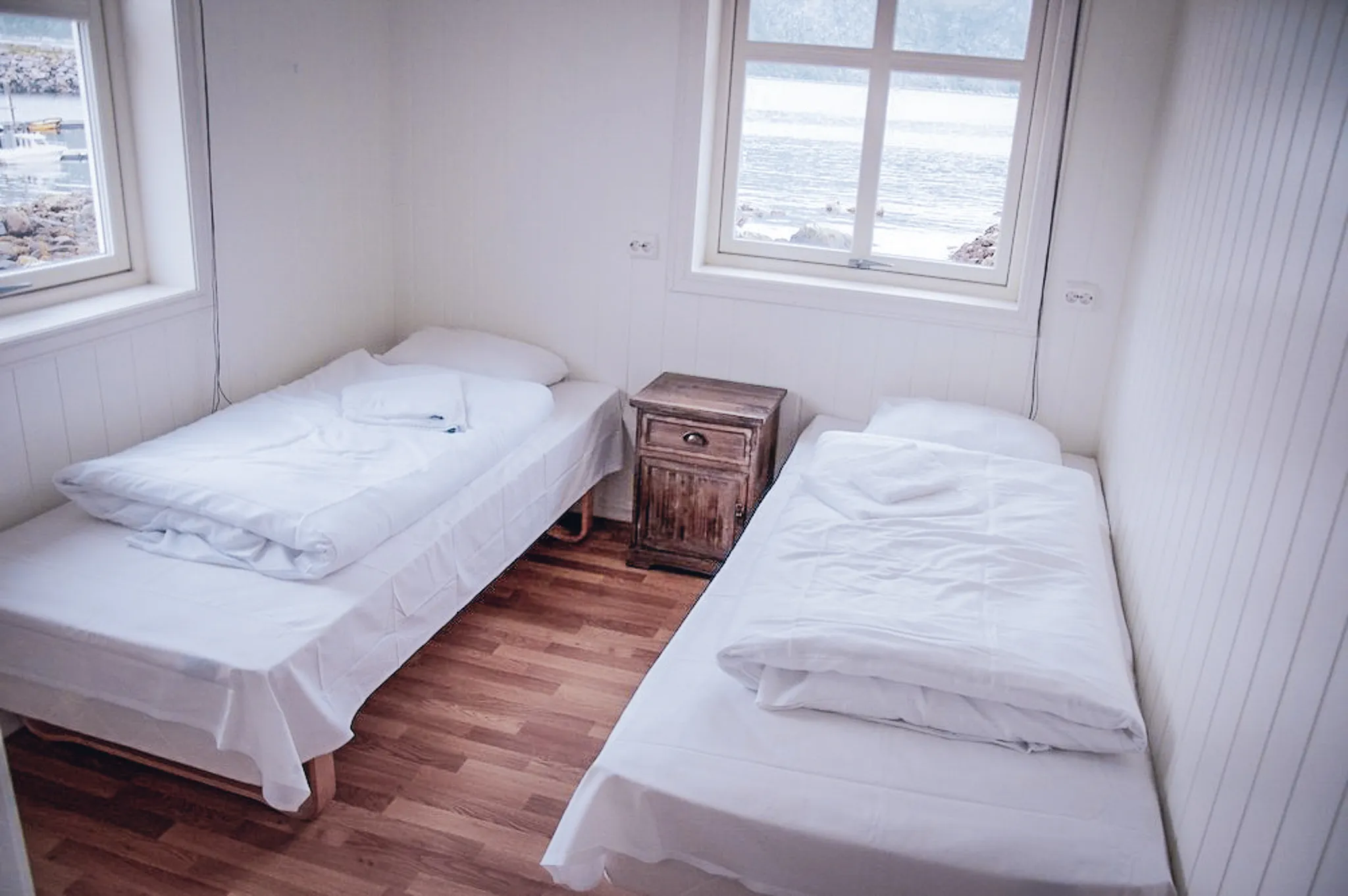 Chambre lumineuse et accueillante avec deux lits simples, vue sur les fjords de Senja.