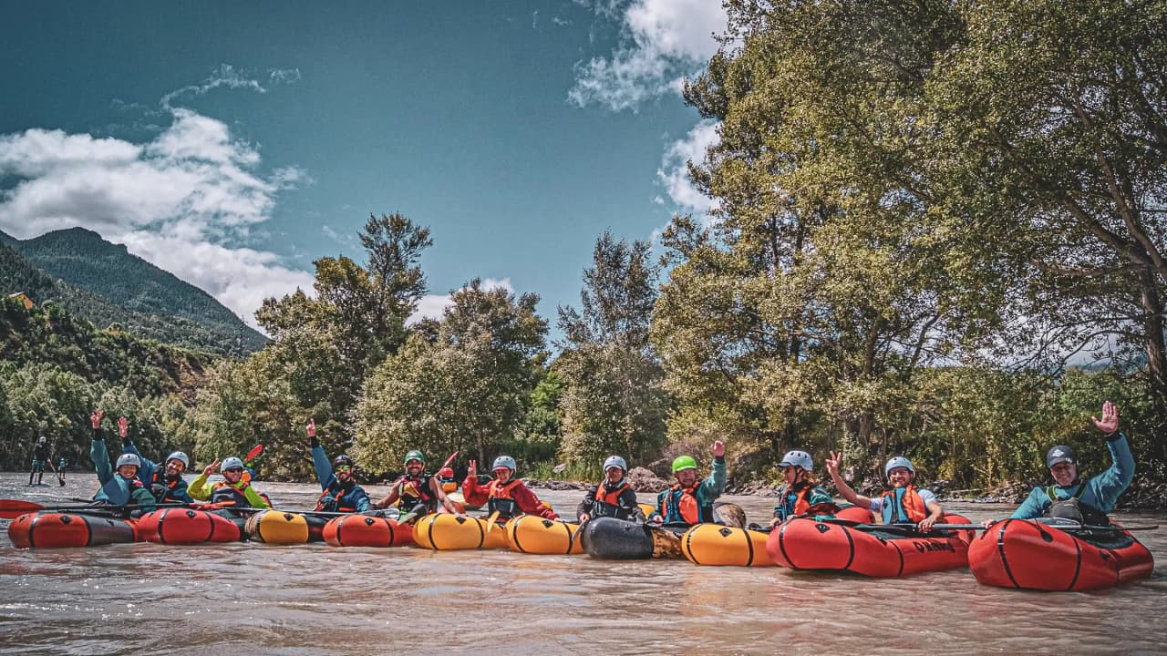 Een vrolijke groep in packrafts op de Durance, omringd door groene bergen en prachtige natuur.