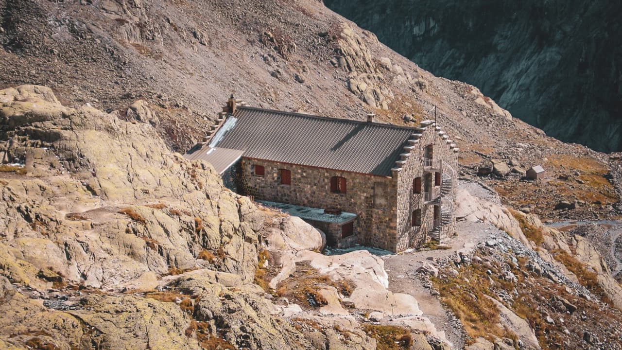 Refuge en pierre au cœur des Écrins, entouré de rochers et de paysages alpins à couper le souffle.
