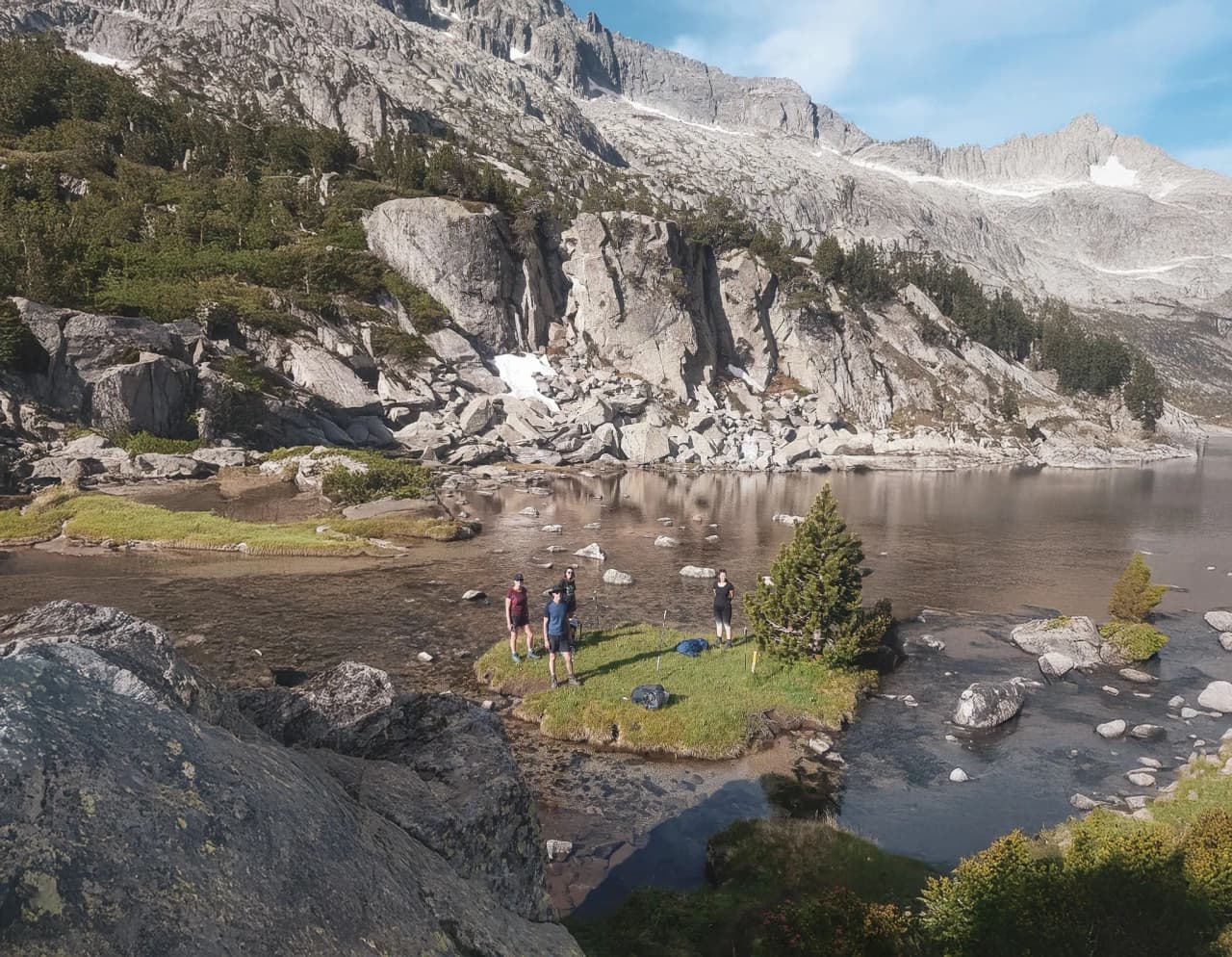 A group of hikers on the edge of a peaceful lake, surrounded by majestic mountains.