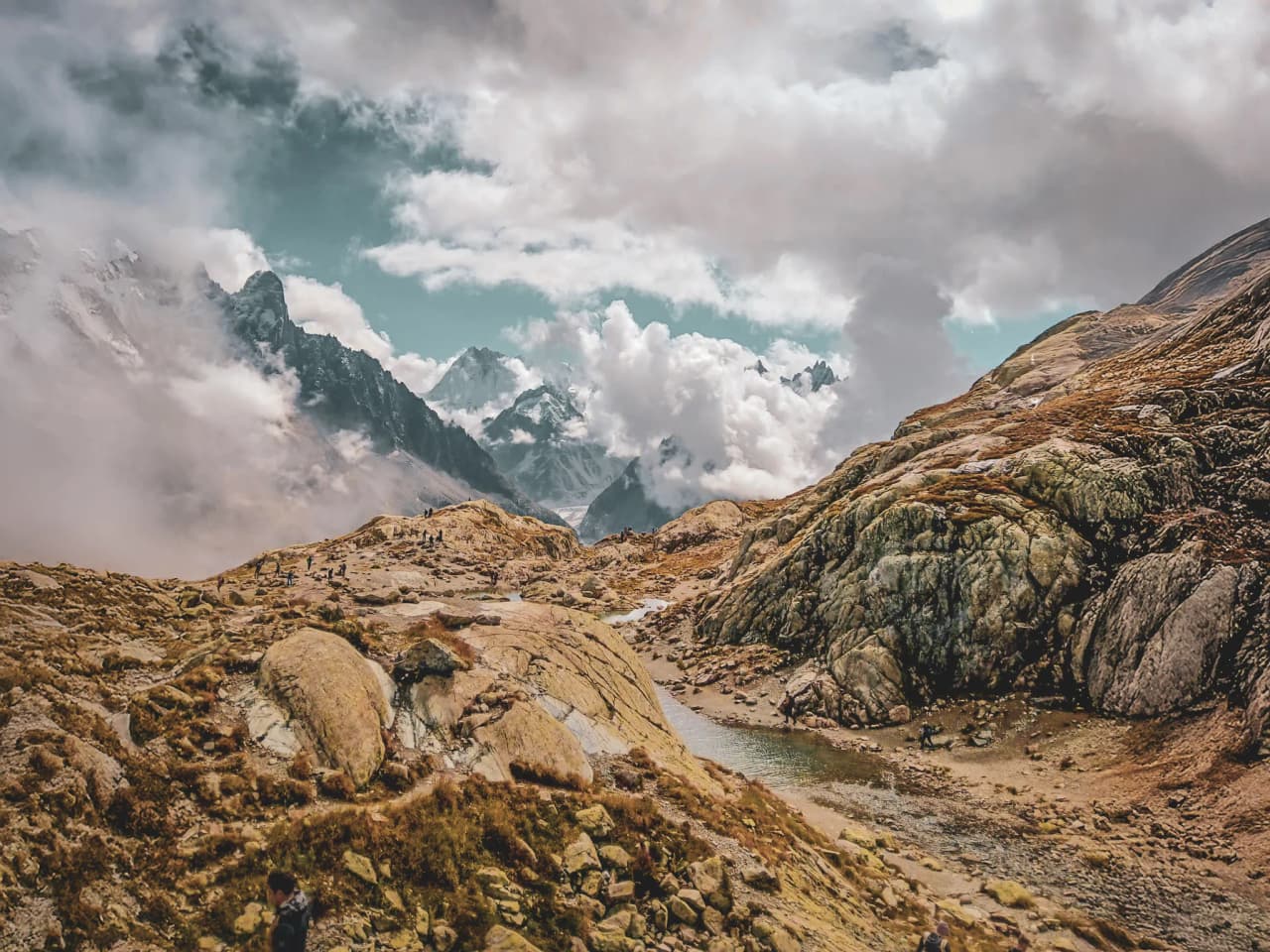 Paysage montagneux majestueux des Alpes, avec des rochers, des nuages et des randonneurs émerveillés.