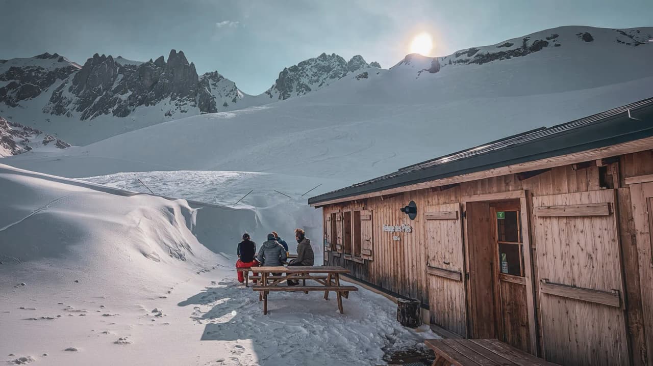 A welcoming wooden hut, with skiers admiring the snow-capped peaks of Mont Blanc.