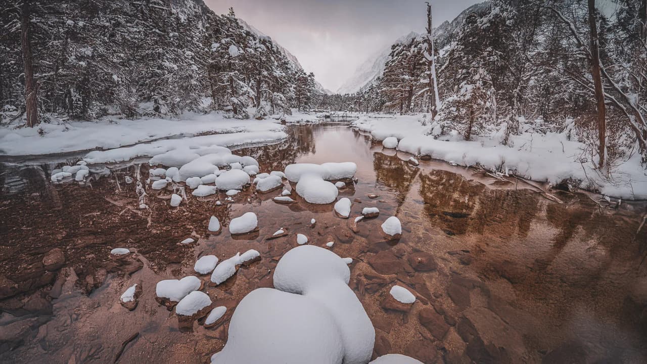A peaceful winter landscape of snow-covered rocks and forests, inviting you to embark on an adventure.
