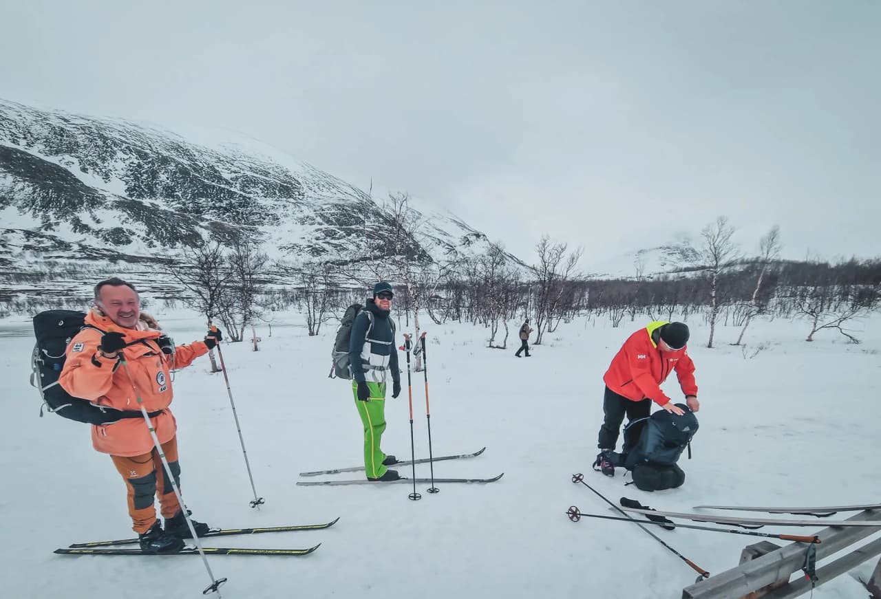 Drie lachende skiërs staan op het punt om de uitgestrekte besneeuwde landschappen van Lapland te verkennen.
