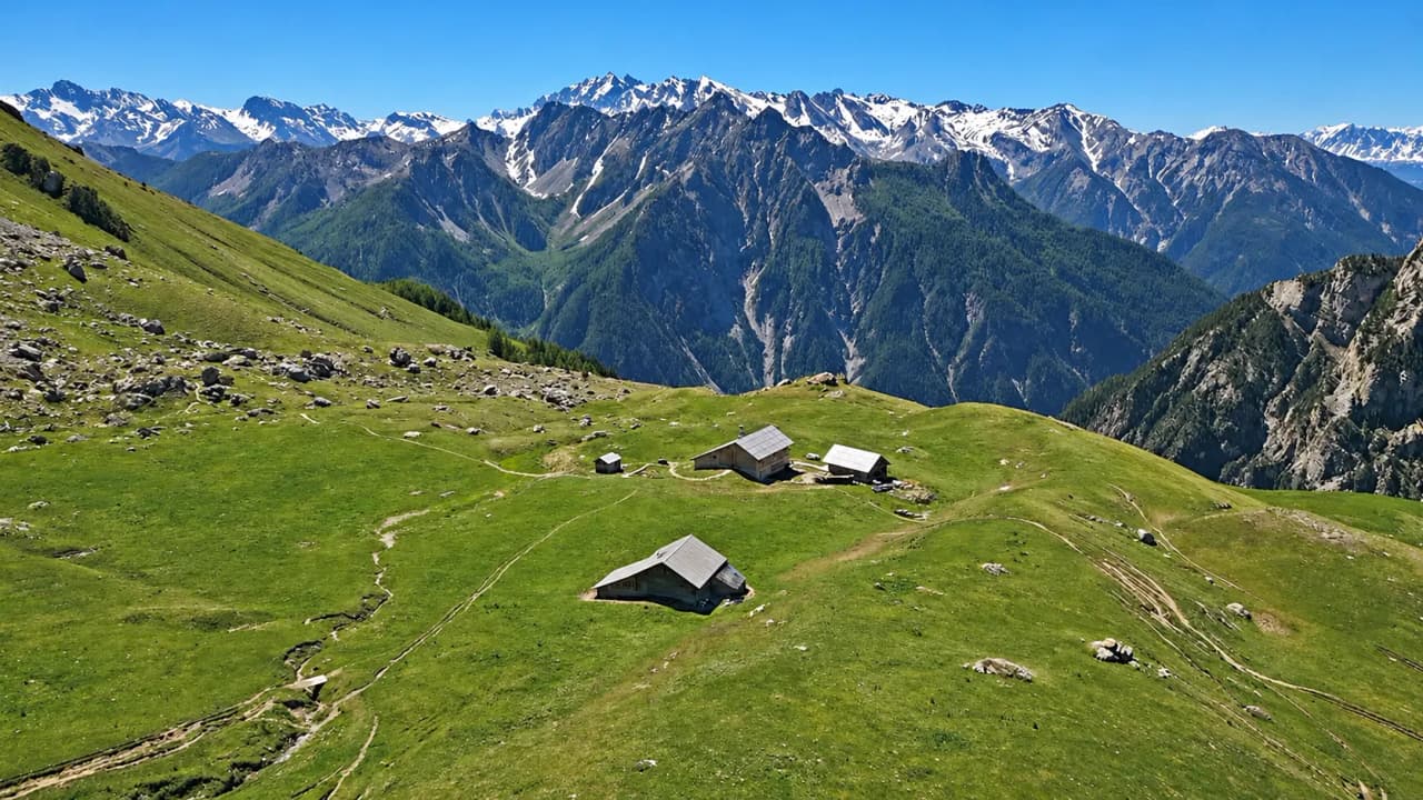Een betoverend uitzicht op het Queyras-gebergte, met pittoreske chalets op een weelderige groene weide.