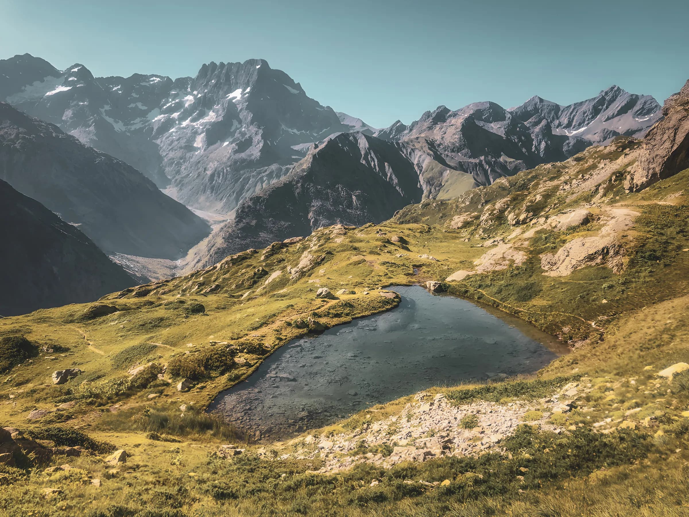 Vue panoramique des montagnes majestueuses des Écrins, avec un lac paisible en premier plan.
