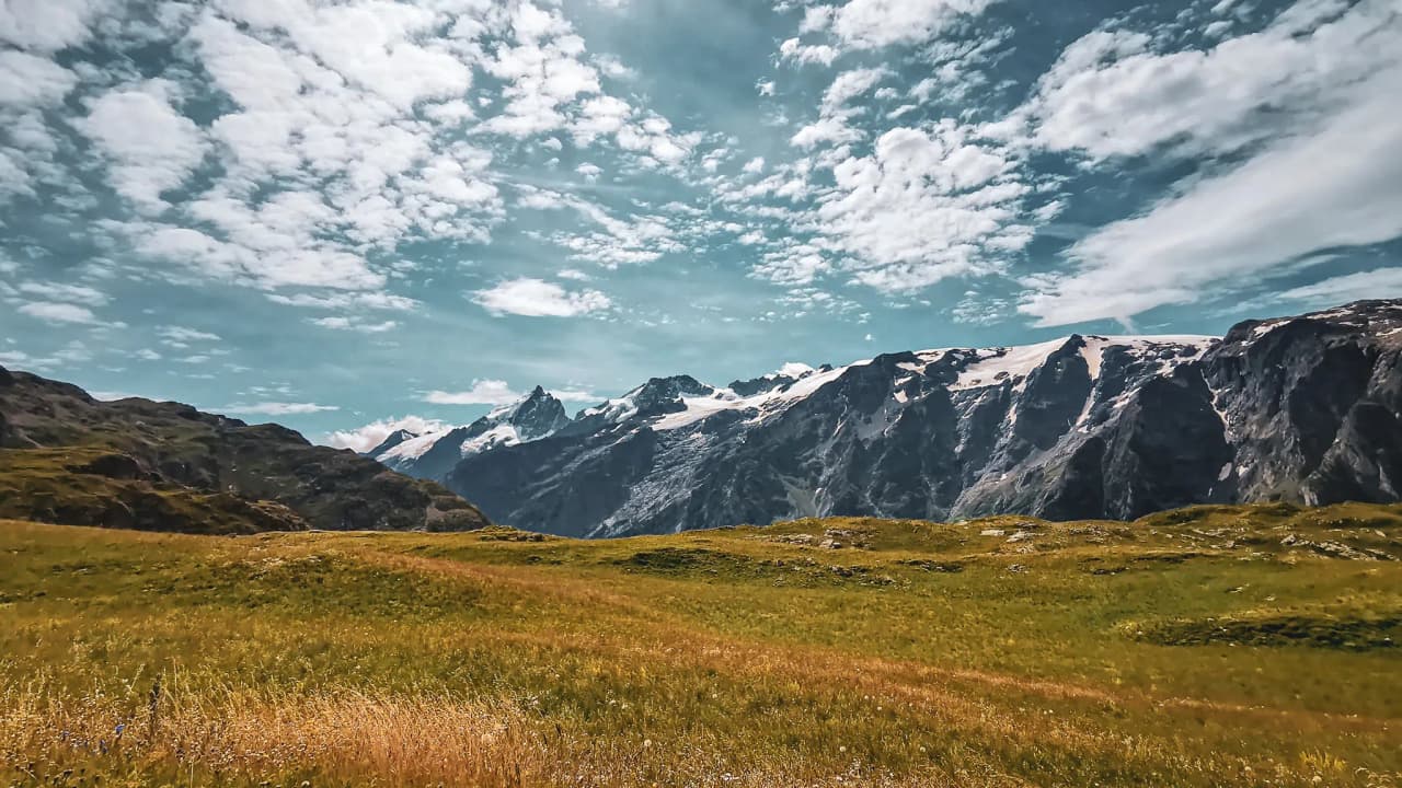 Panorama majestueux du plateau d'Emparis, montagnes et nuages dans un ciel lumineux.