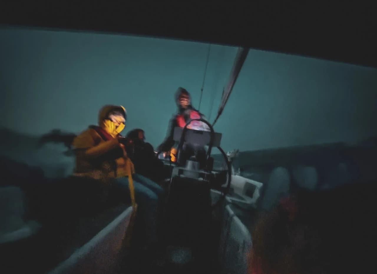 Team in action on a sailboat, dark waves under a starry sky at sea. A night-time adventure!