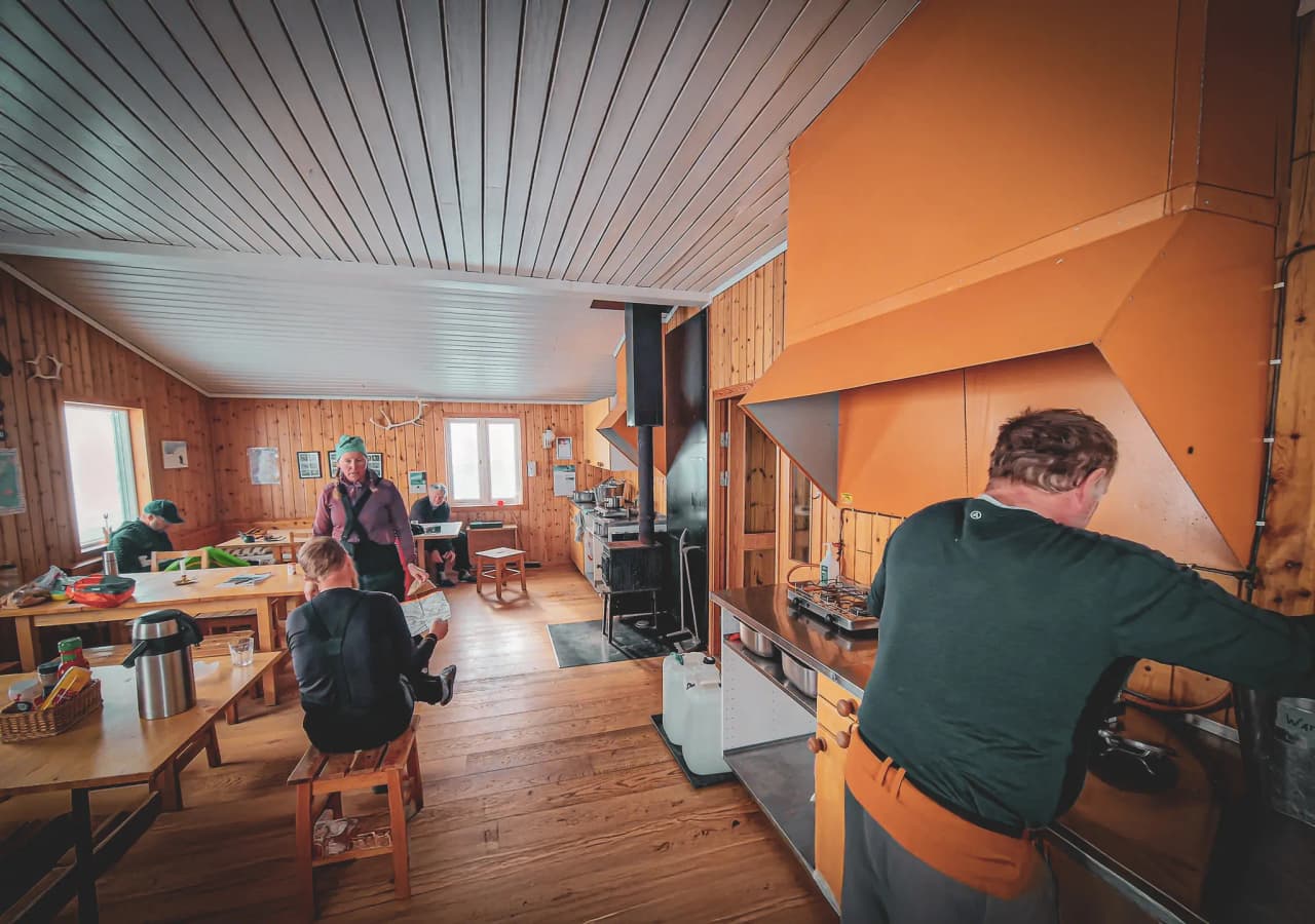 Een gezellig Berghut in Lapland, met een vriendelijke keuken en reizigers op vakantie, klaar om Kungsleden te verkennen.