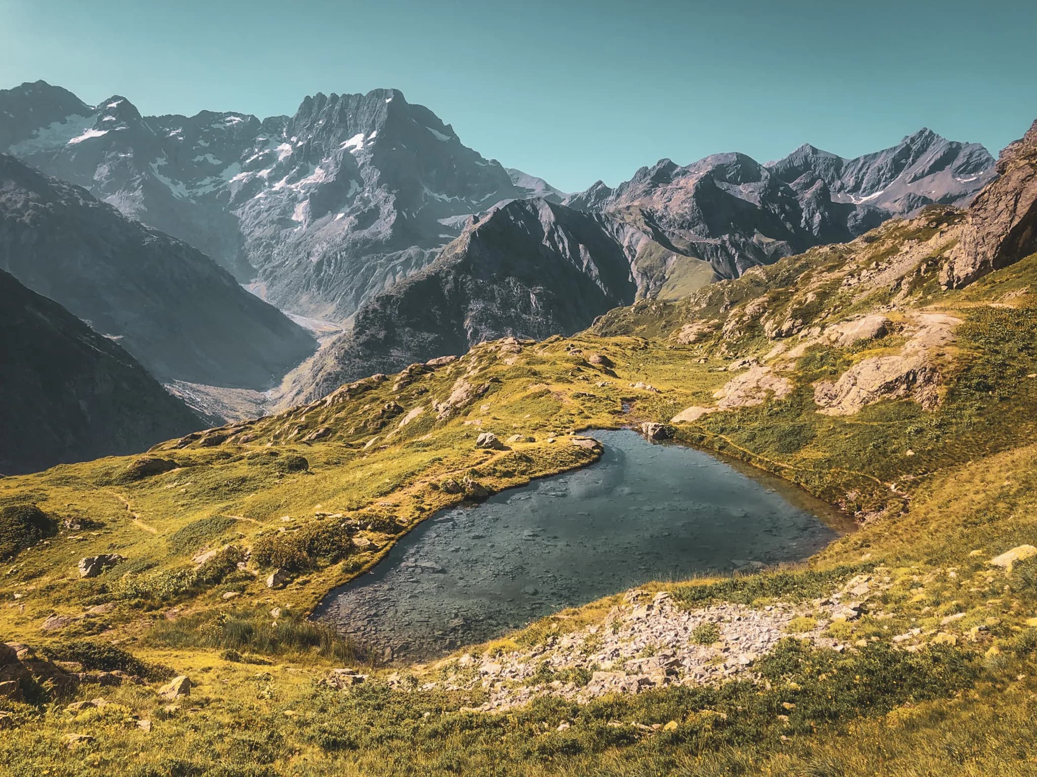 Een vredig meer omringd door majestueuze bergen onder een stralend blauwe hemel.