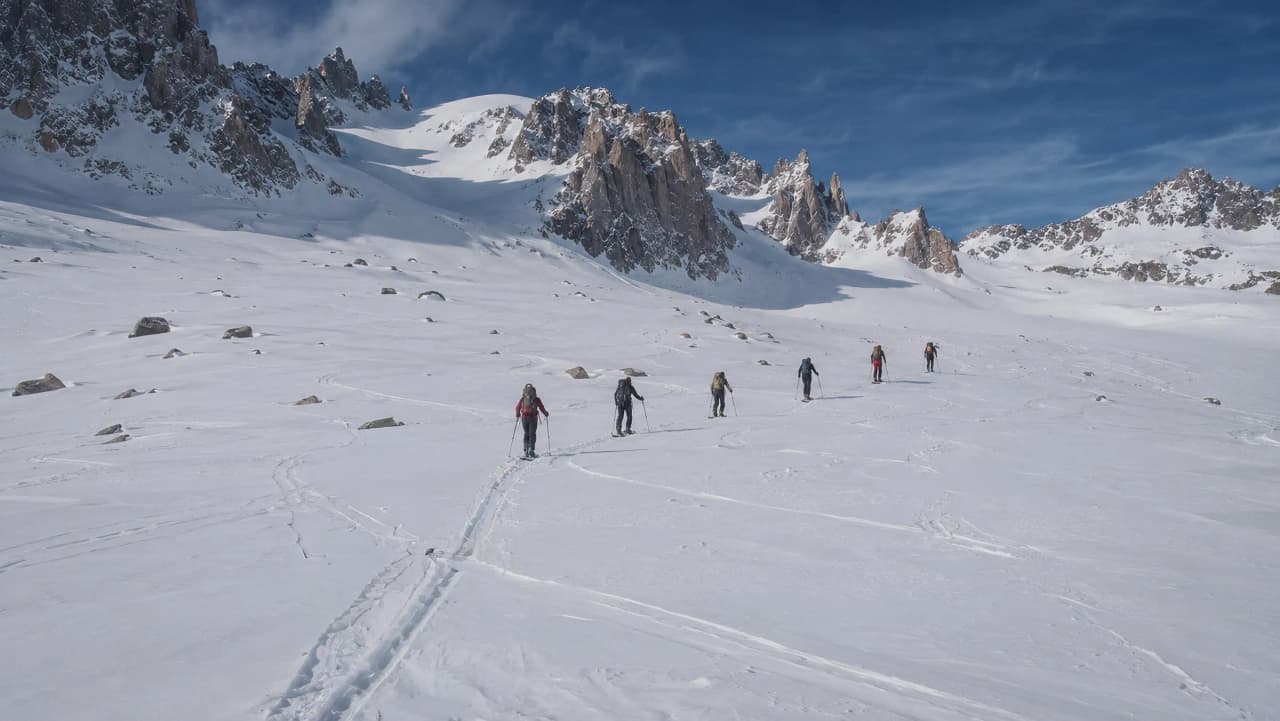 Groupe de snowboardeurs progressant sur un vaste glacier au pied des majestueuses montagnes de Chamonix.