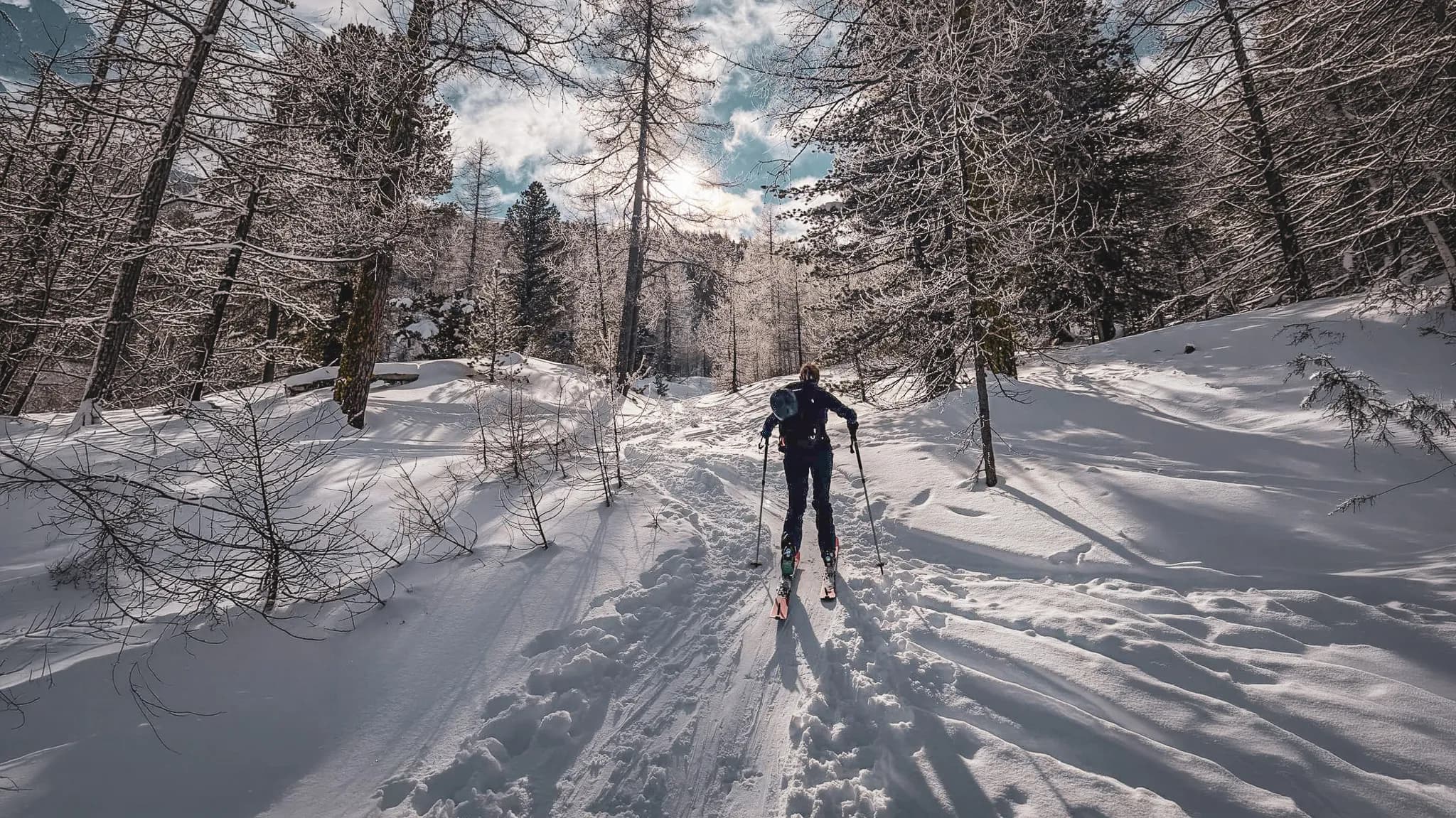 Skieur en pleine nature, traversant un paysage enneigé et ensoleillé des crêtes du Queyras.