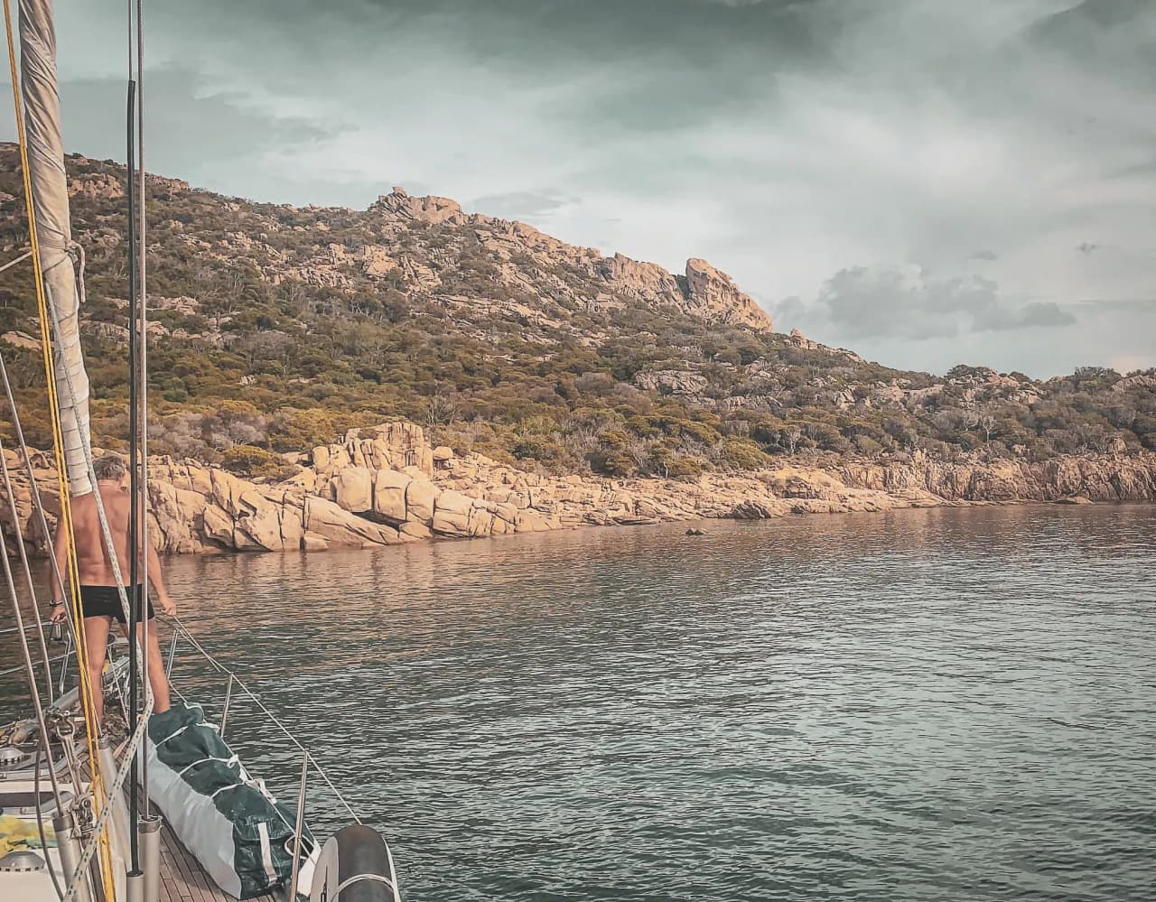 Un voilier paisiblement ancré près de côtes rocheuses de Corse, évoquant l'aventure et la nature.