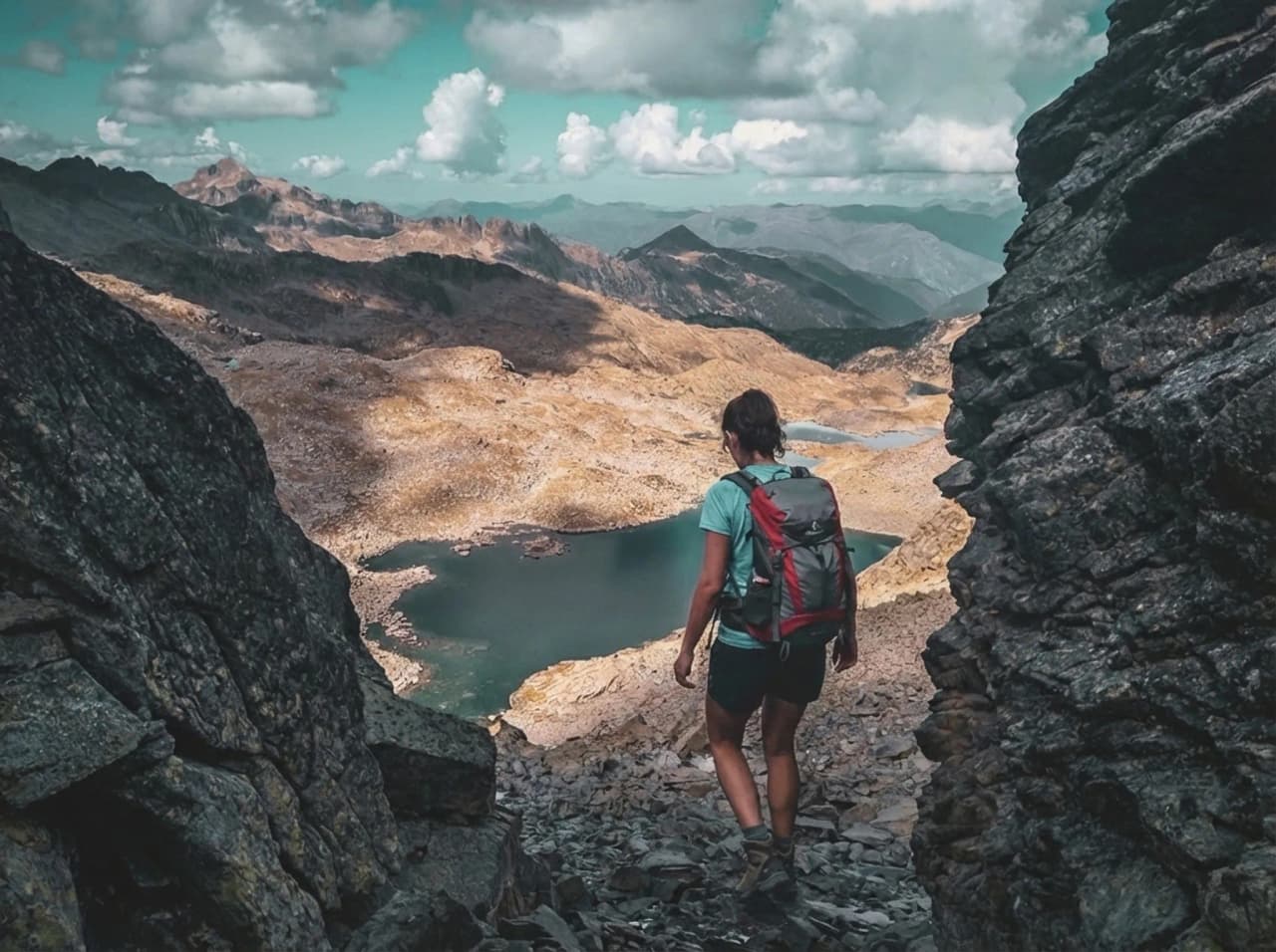 A hiker exploring a spectacular alpine landscape, surrounded by lakes and majestic mountains.