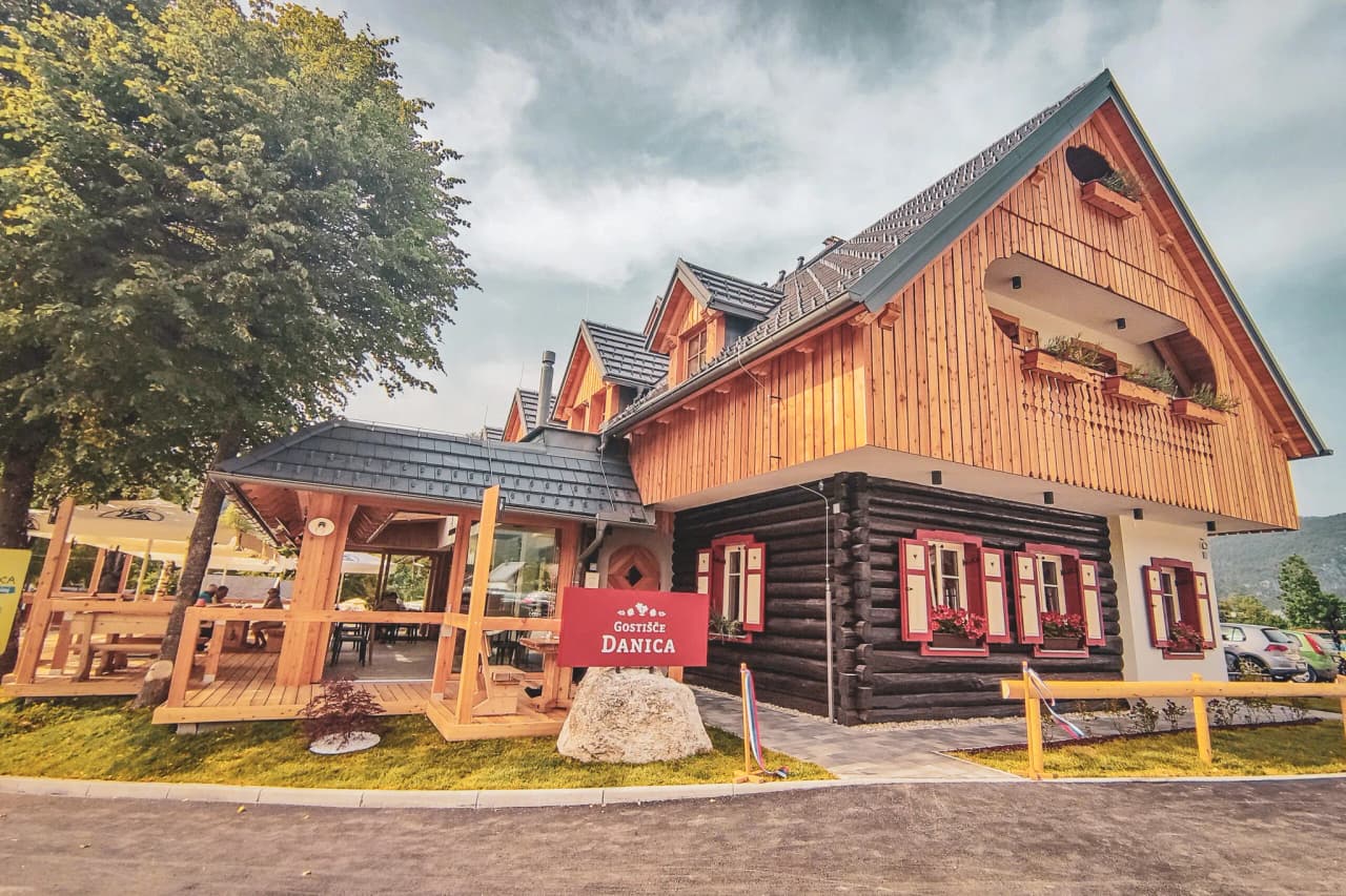 A natural landscape with a turquoise river winding through a valley surrounded by lush green mountains. Scattered rocks emerge from the water, adding a fascinating contrast. The banks are lined with