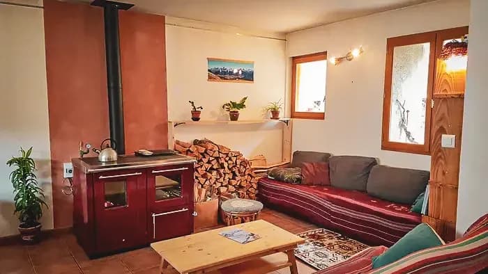 Gezellige lounge met houtkachel, groene planten en comfortabele banken, ideaal na een dag paardrijden.