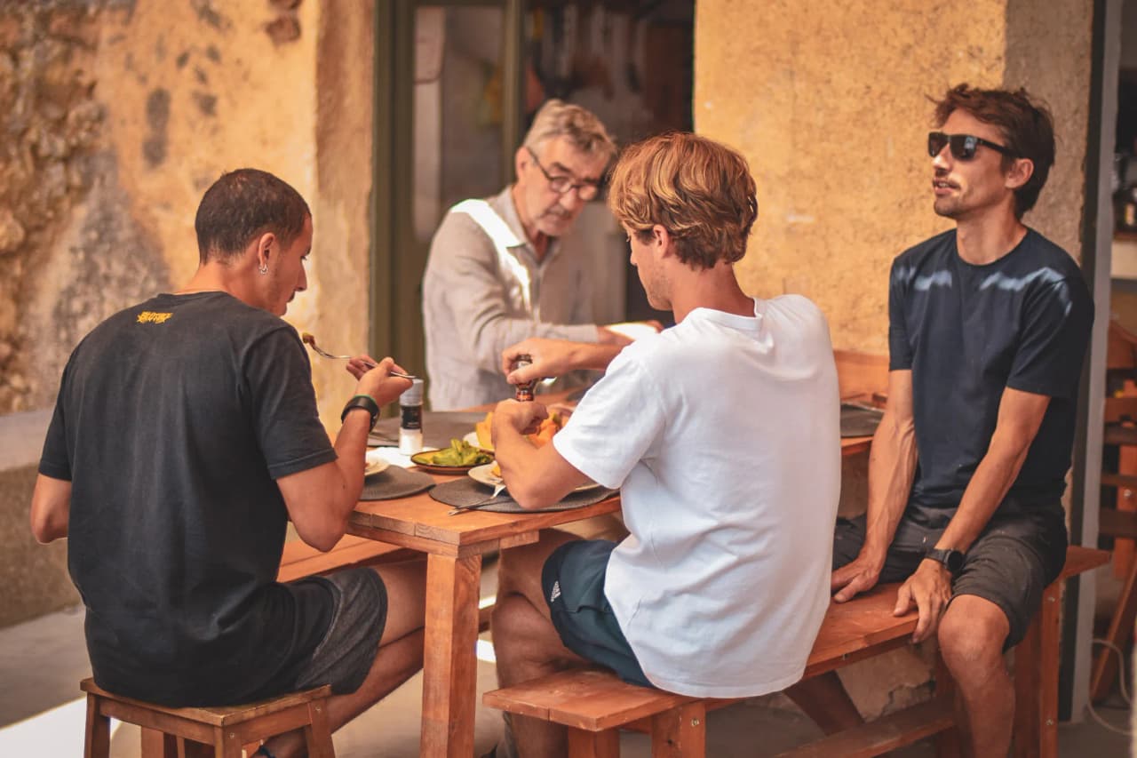 Vier vrienden genieten van een gezellige maaltijd midden in de natuur, omgeven door Italiaanse charme.