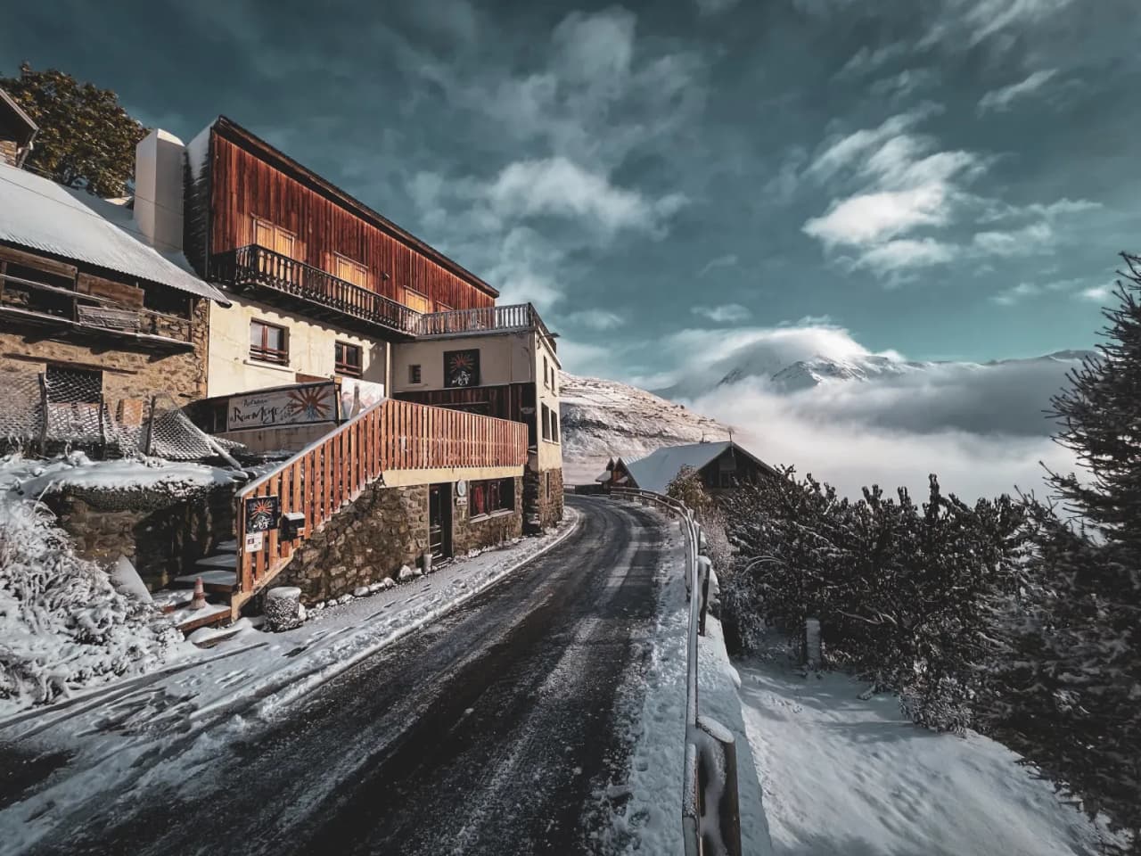 Charmante rue enneigée à La Grave, entourée de montagnes majestueuses et de maisons typiques.