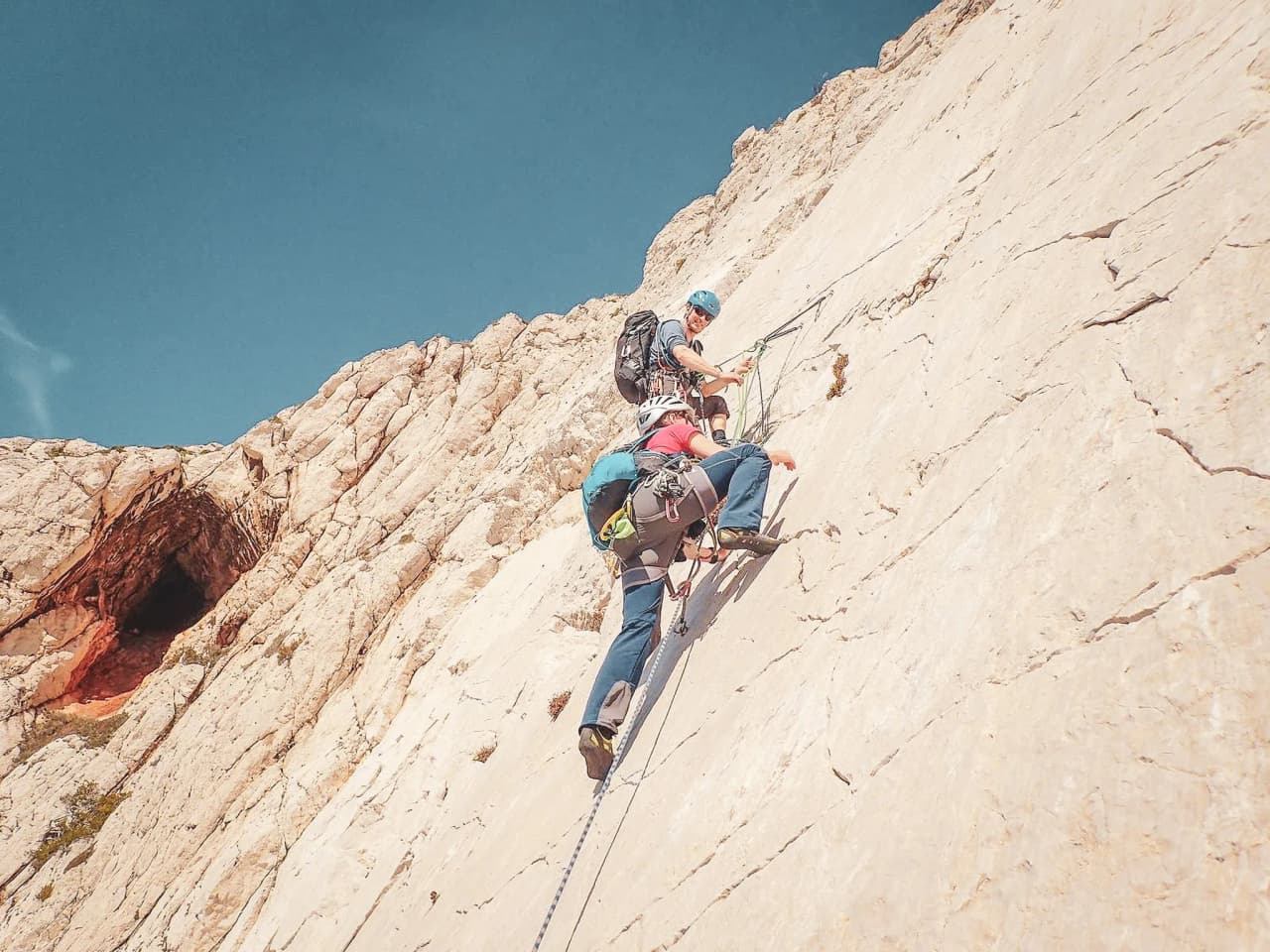 Deux grimpeurs escaladent une falaise ensoleillée des Calanques de Marseille, aventure mémorable.