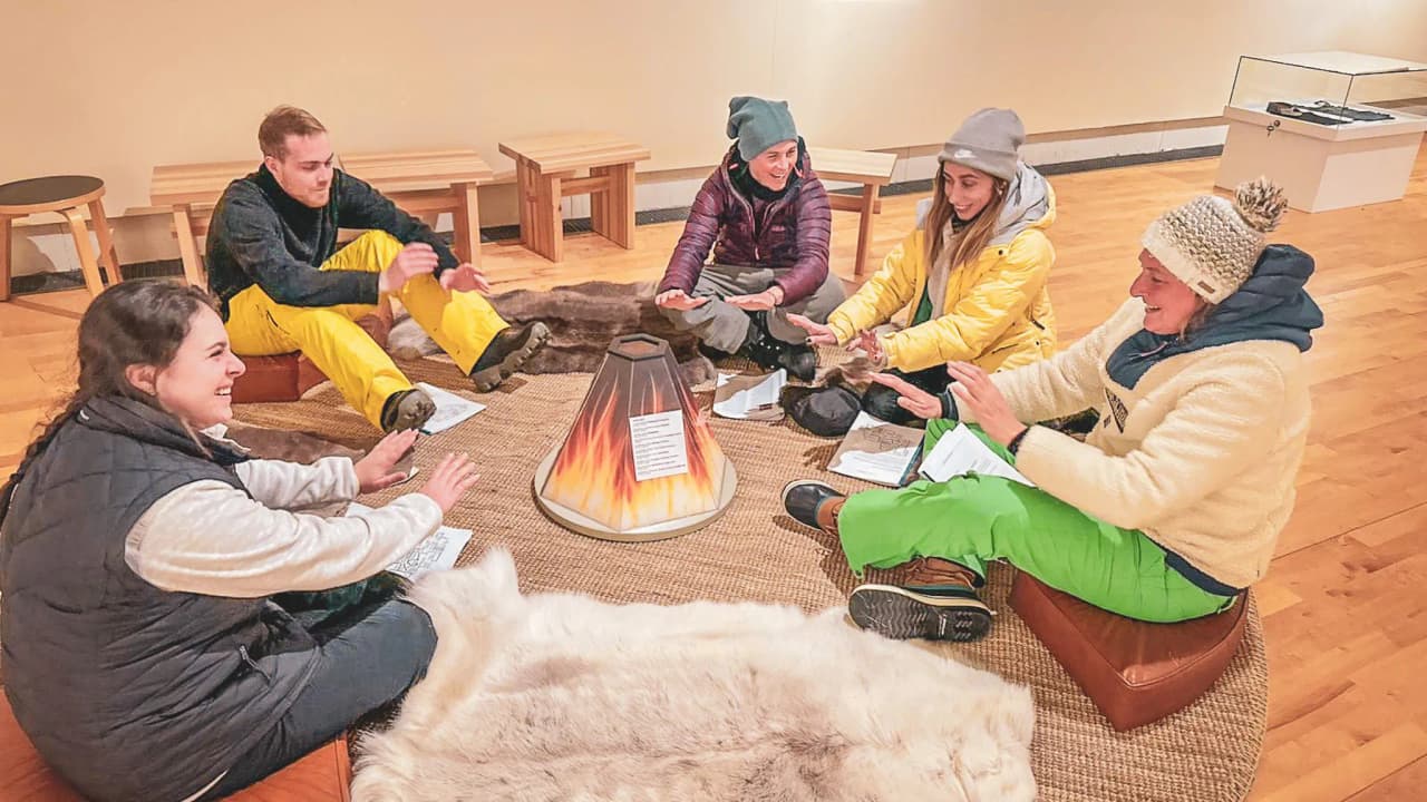 A group sharing a convivial moment around a fire in the middle of Lapland in winter.