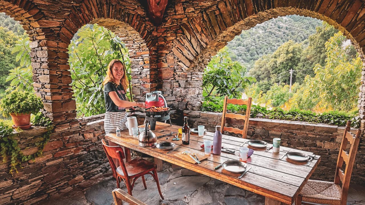 Une table en bois sous un arc en pierre, avec des mets savoureux et une belle vue sur la nature.