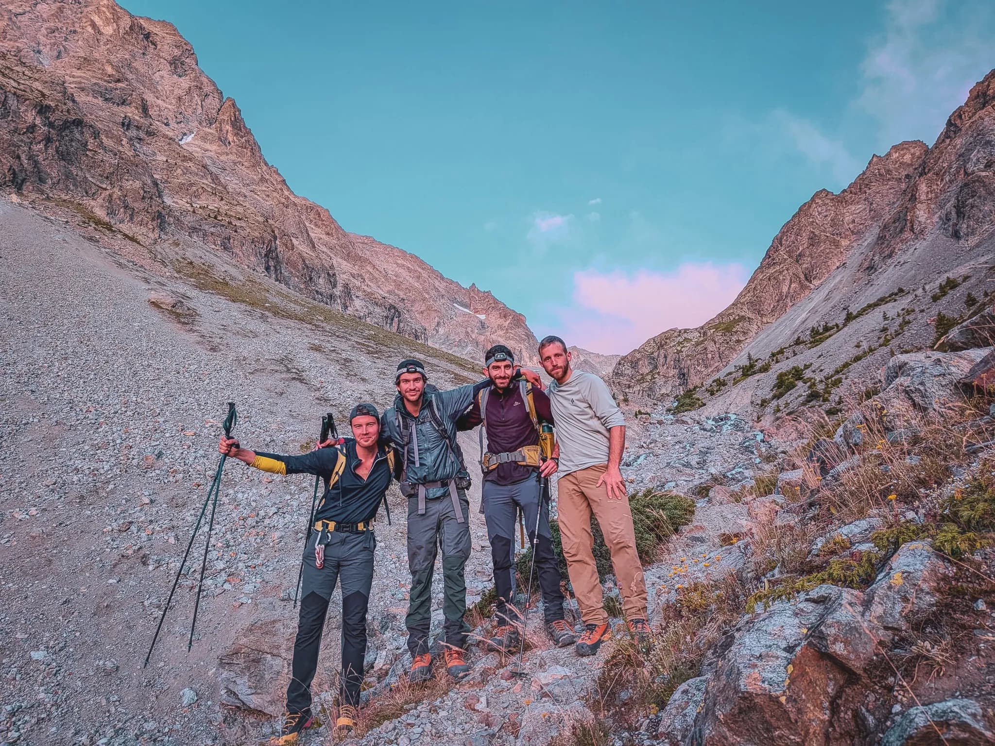 Vier lachende klimmers poseren midden in een majestueus berglandschap in de Écrins.