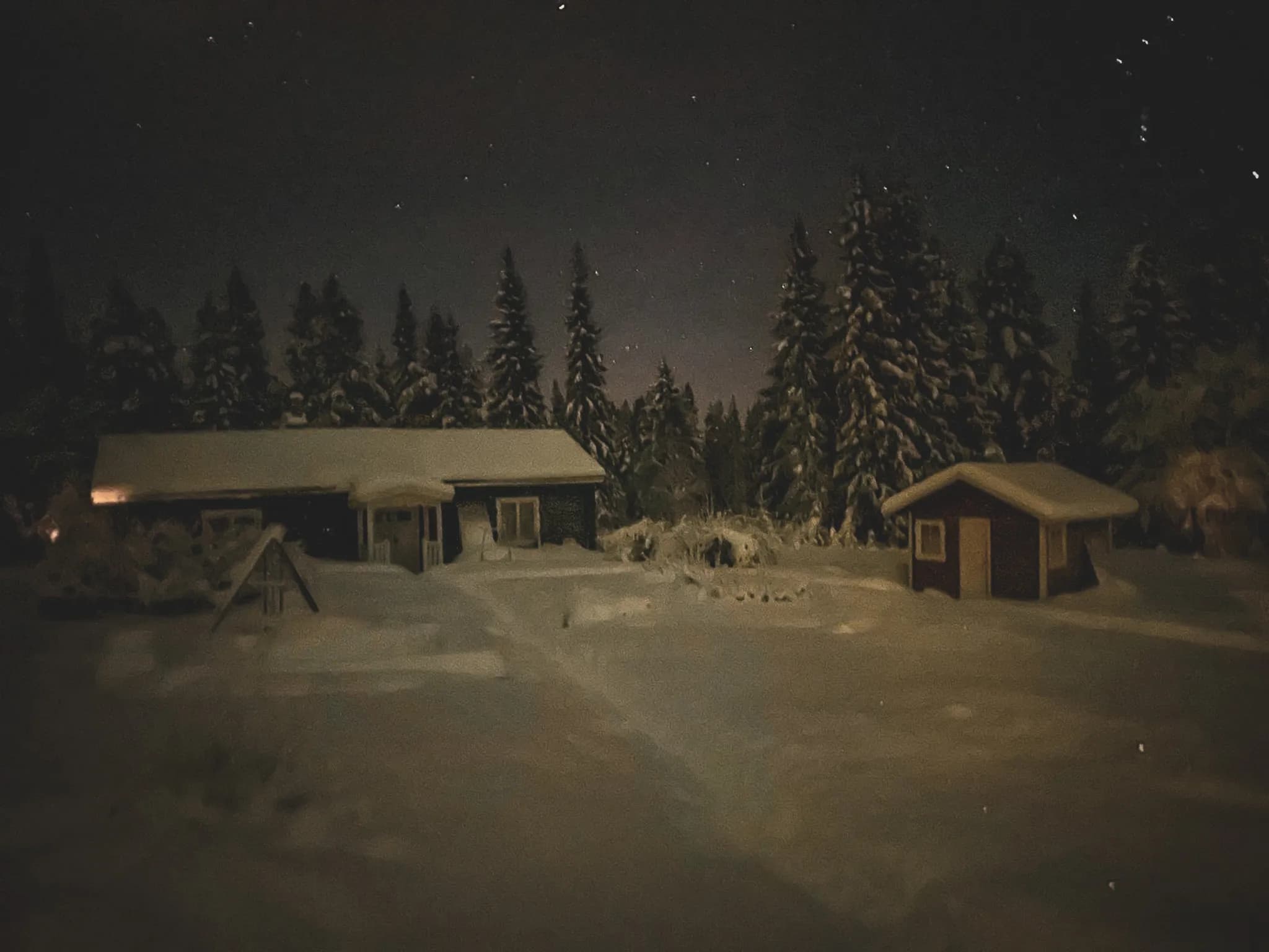 Een nachtscène in Zweeds Lapland, met besneeuwde chalets onder een sterrenhemel.